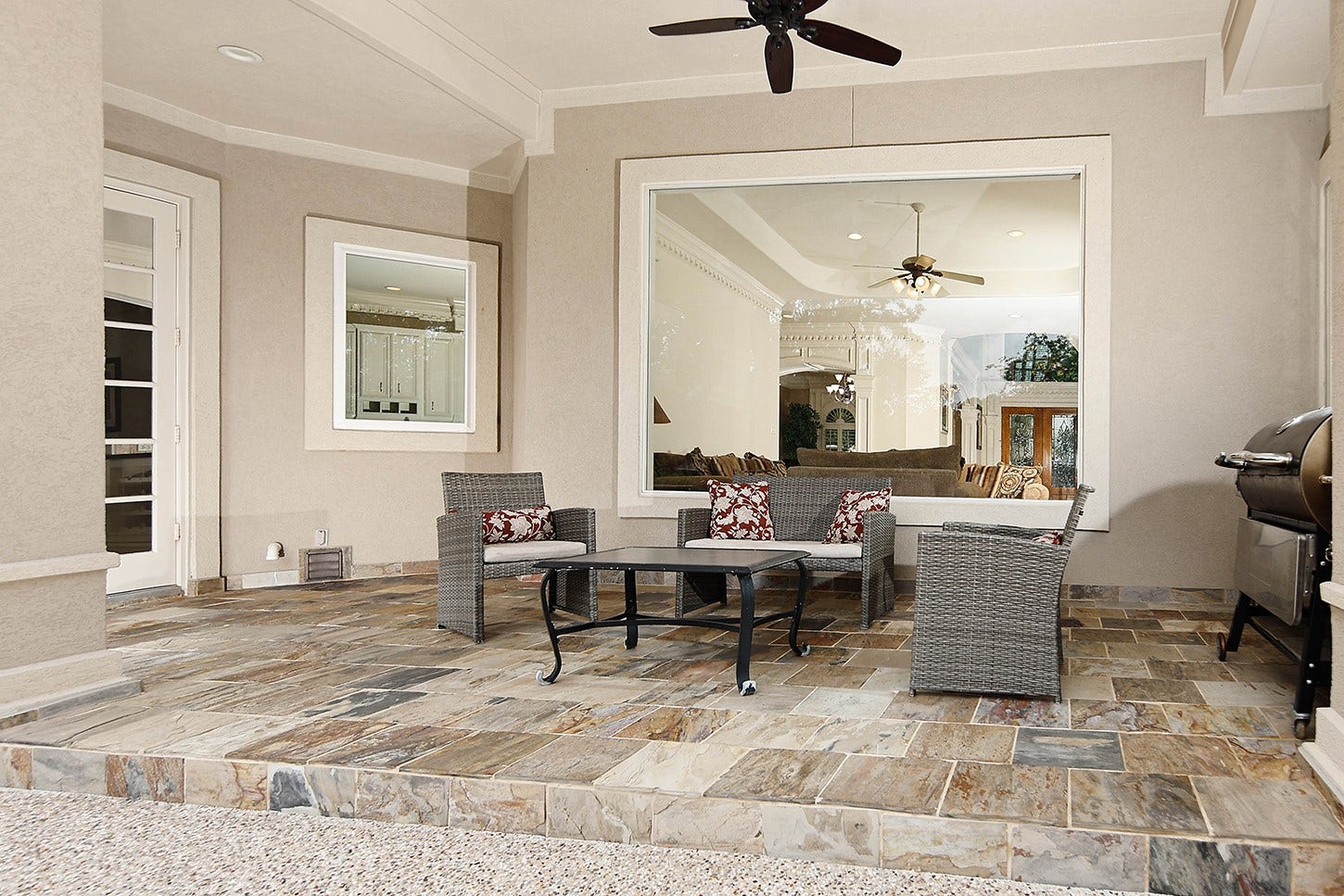 10 Snow Pond Place, The Woodlands, TX 77382 The covered lanai features slate tile decking and a ceiling fan, creating an elegant space for outdoor lounging, dining, and grilling. This area offers seamless access from both the casual dining room and the primary suite.