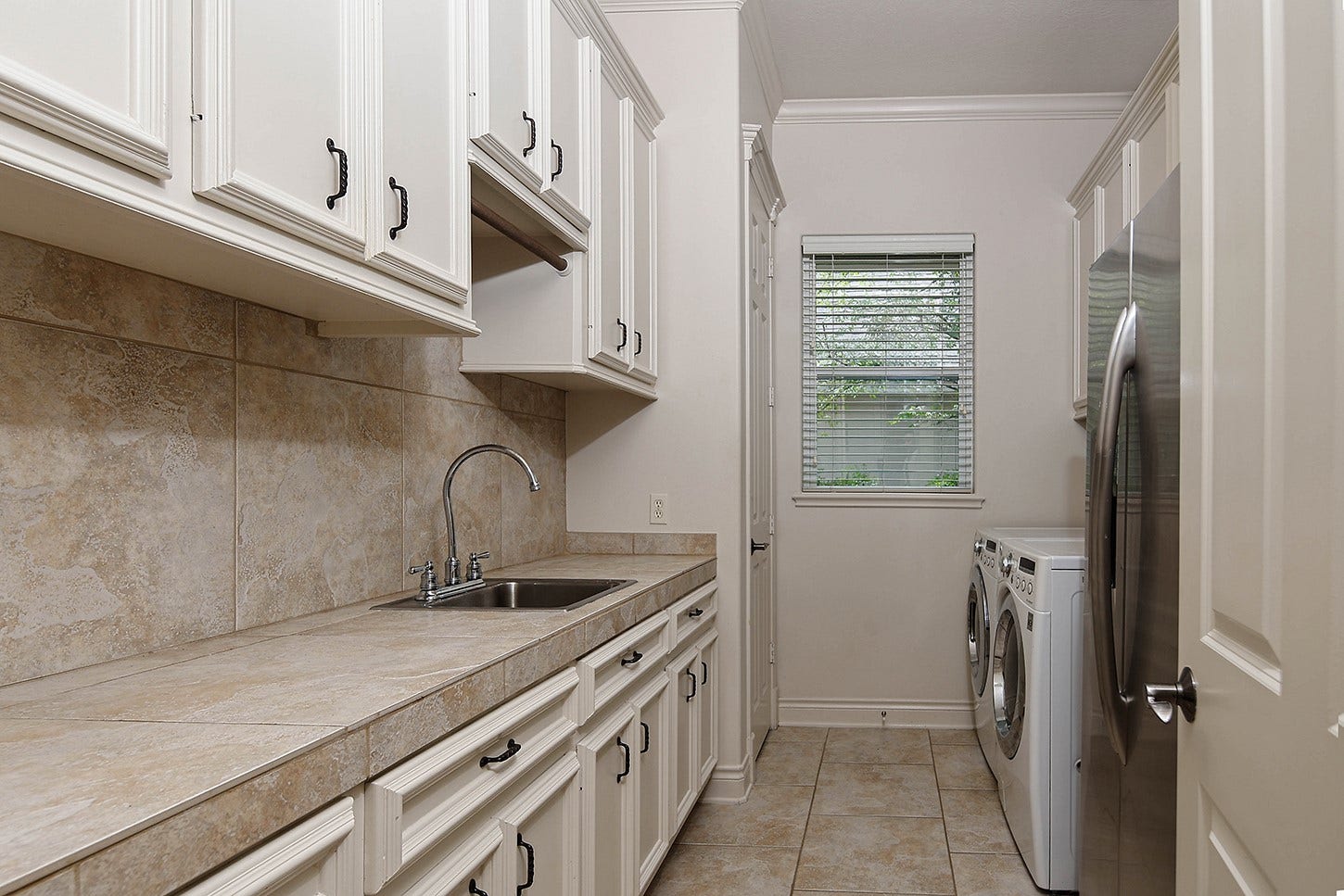 10 Snow Pond Place, The Woodlands, TX 77382 This premium laundry room features expansive counter space, generous cabinetry, and additional capacity for an auxiliary refrigerator and supplementary storage.