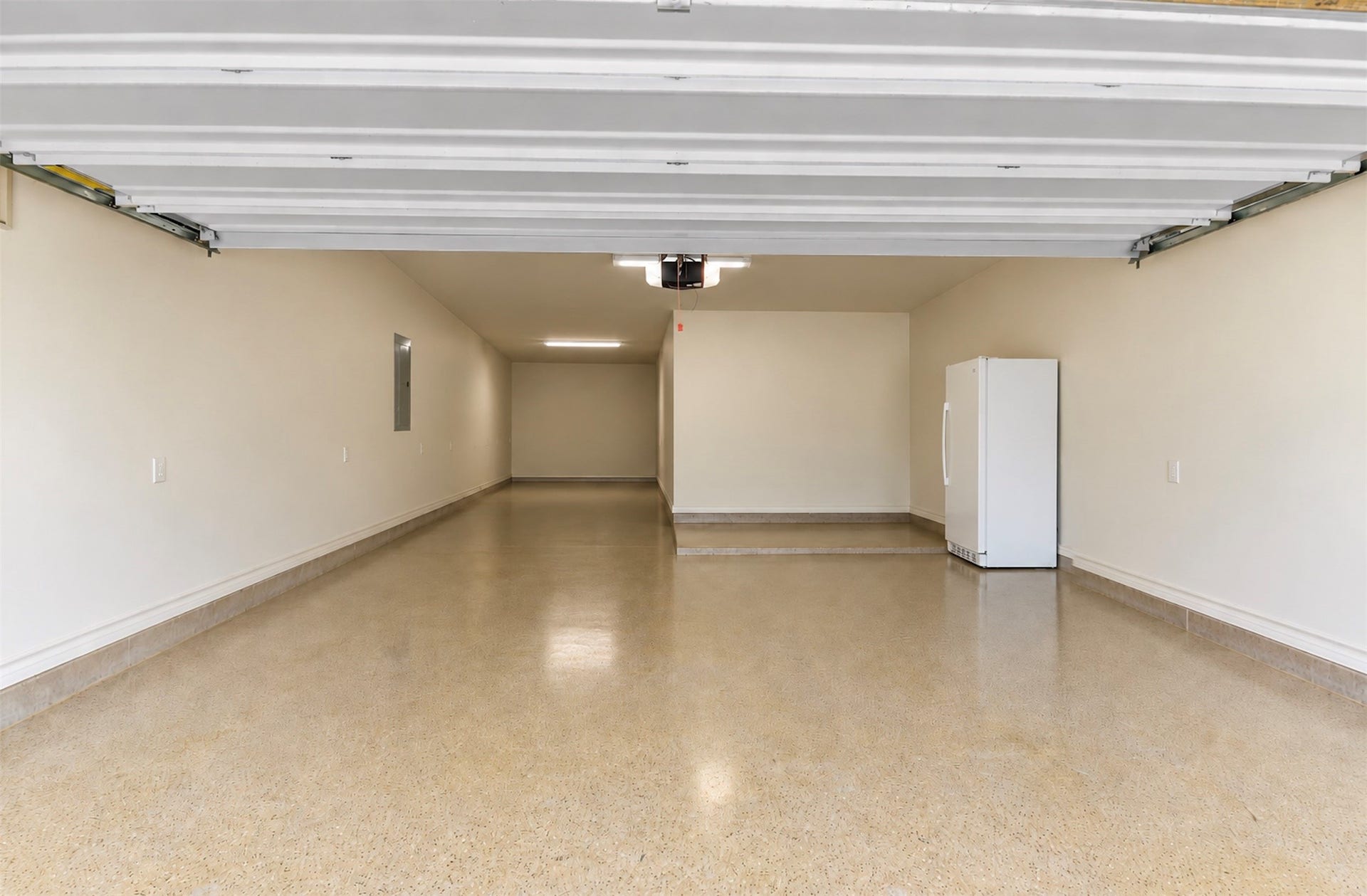 119 Finchfield Place, Montgomery, TX 77316 Spacious tandem garage with an extended parking or storage area and durable finished flooring. (Fridge in garage can stay). (AI Adjusted to show space)