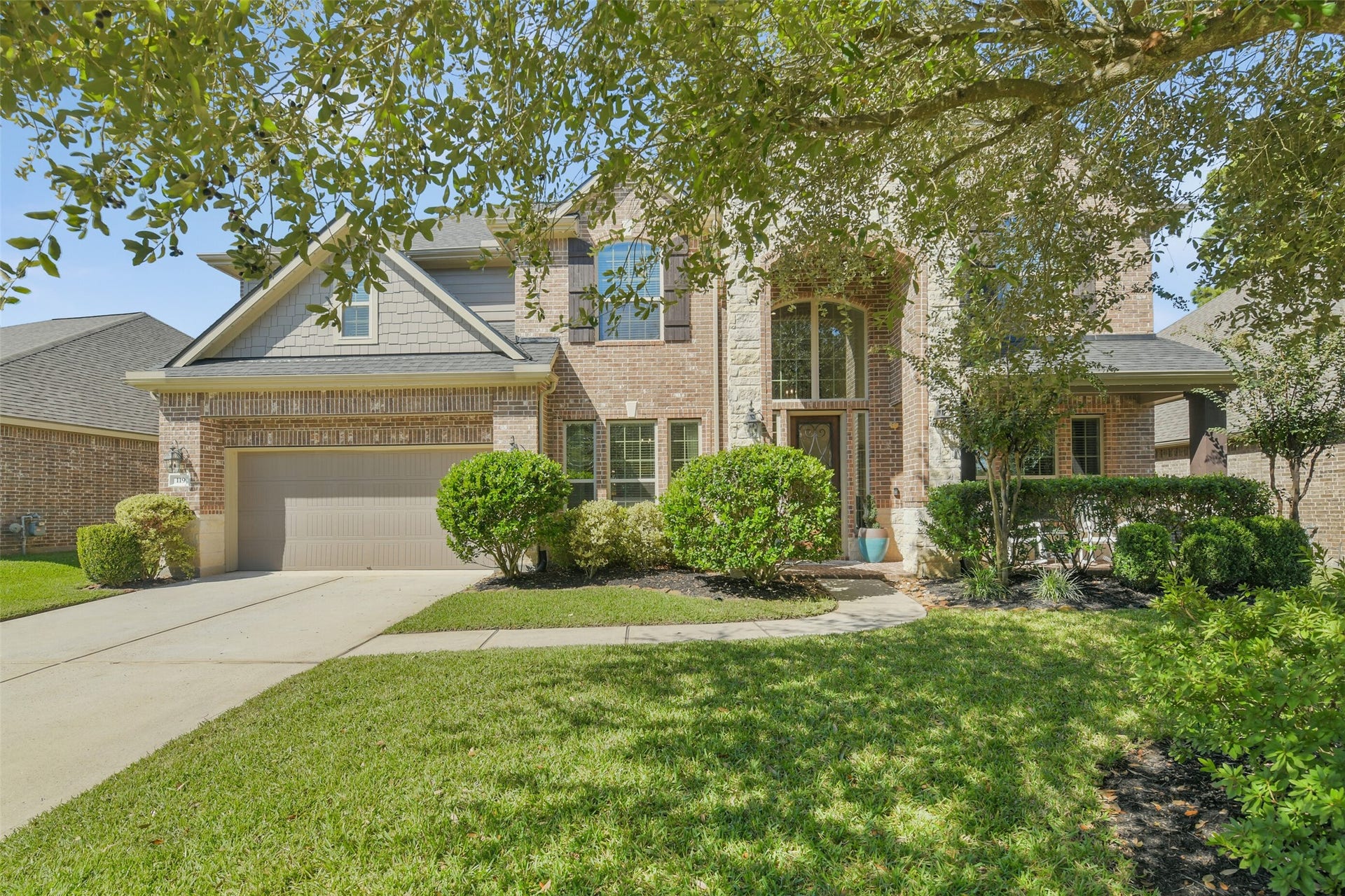 119 Finchfield Place, Montgomery, TX 77316 Beautiful two-story brick home with inviting curb appeal, mature trees, and a spacious driveway. Welcoming front elevation surrounded by manicured landscaping and a lush green lawn.