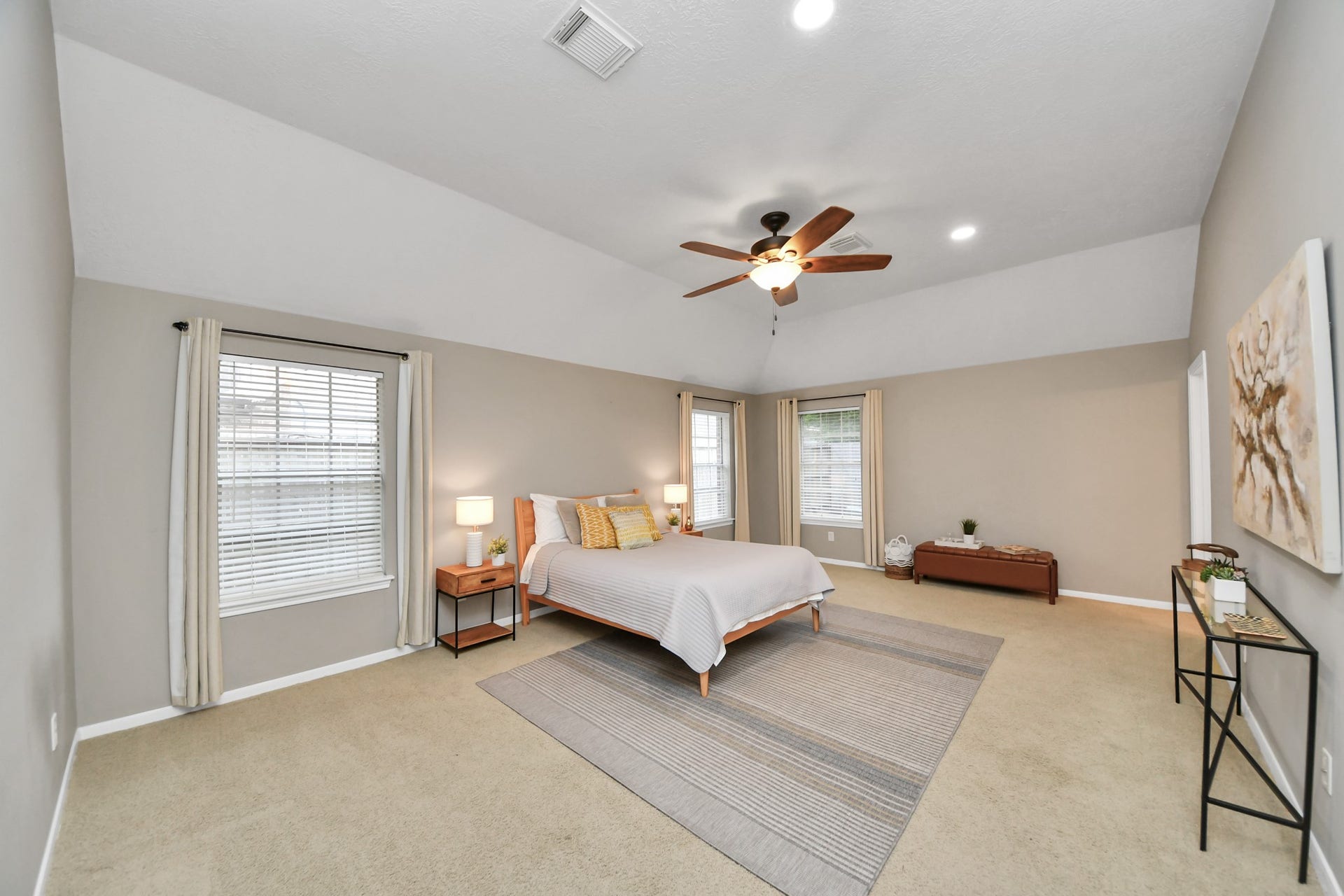 The spacious primary bedroom features high ceilings, large windows, and plenty of room for your furniture, with space left for a sitting area.