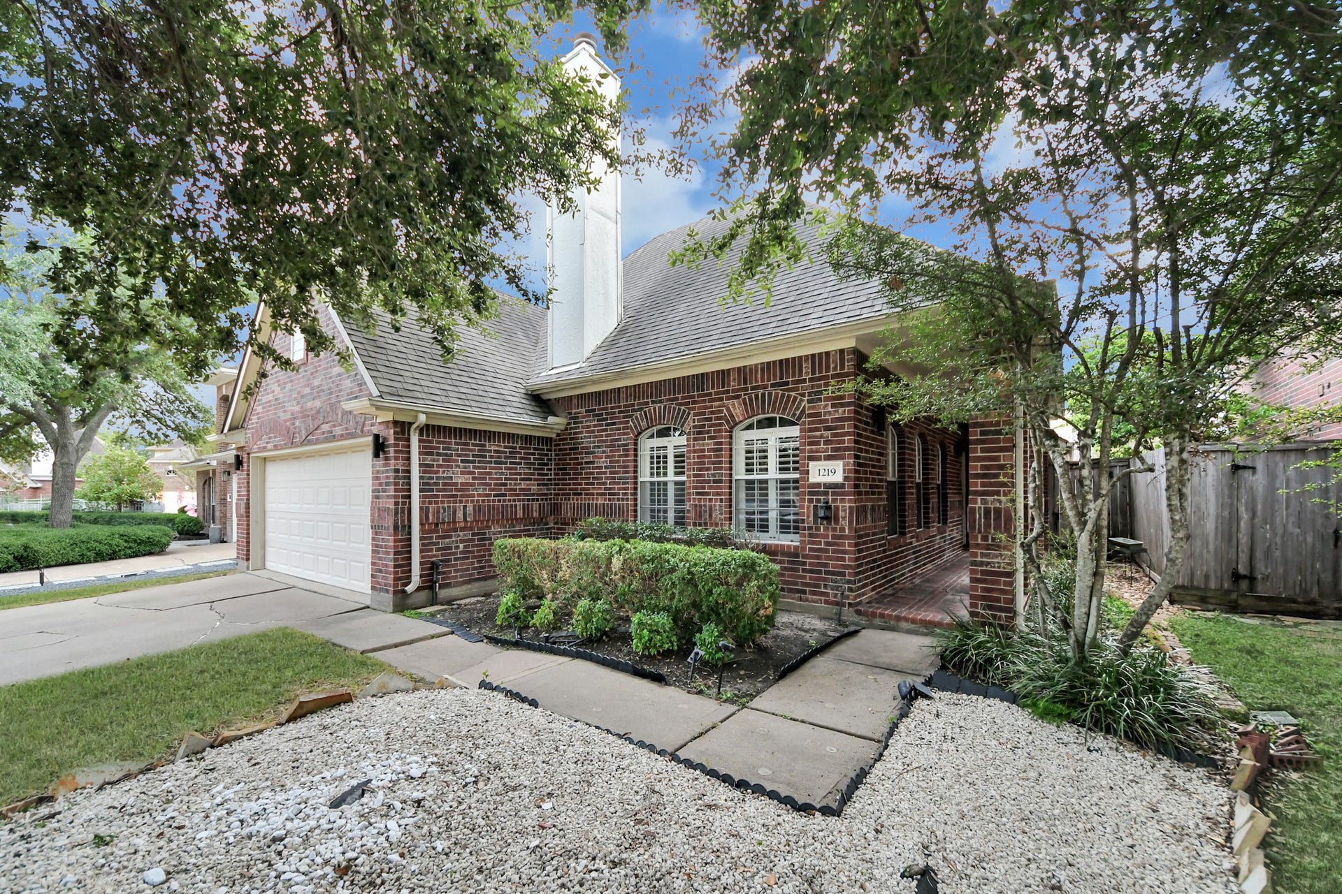 Mature trees and a covered brick porch welcome you to this one-story home in the gated community of Charlton Park.
