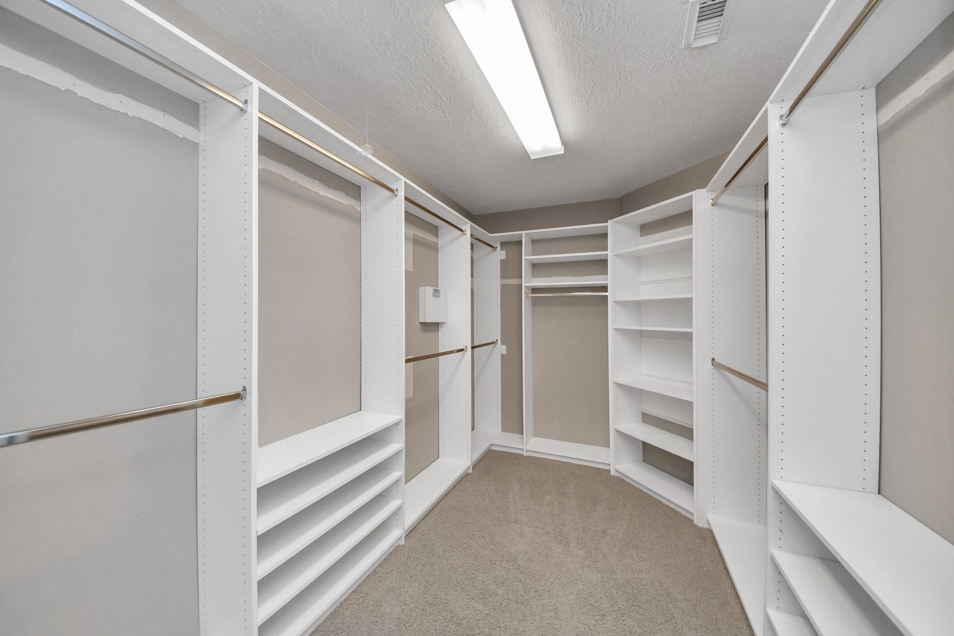 An oversized walk-in closet with plenty of hanging space and built-in shelving for shoes, bags, and folded clothes. A great feature of the primary suite!