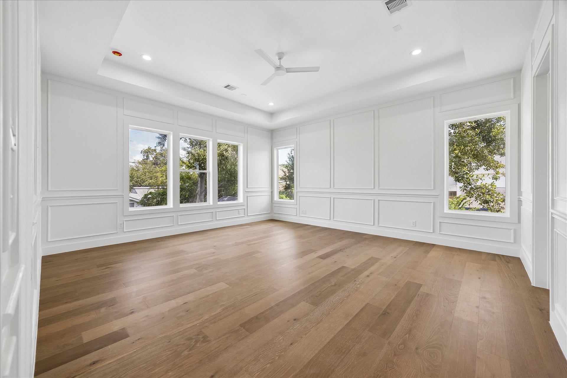 1726 Chantilly Lane, Houston, TX 77018 The primary bedroom features a tray ceiling, paneled walls and a broad bank of windows. Wood flooring gives the room a warm, continuous finish.