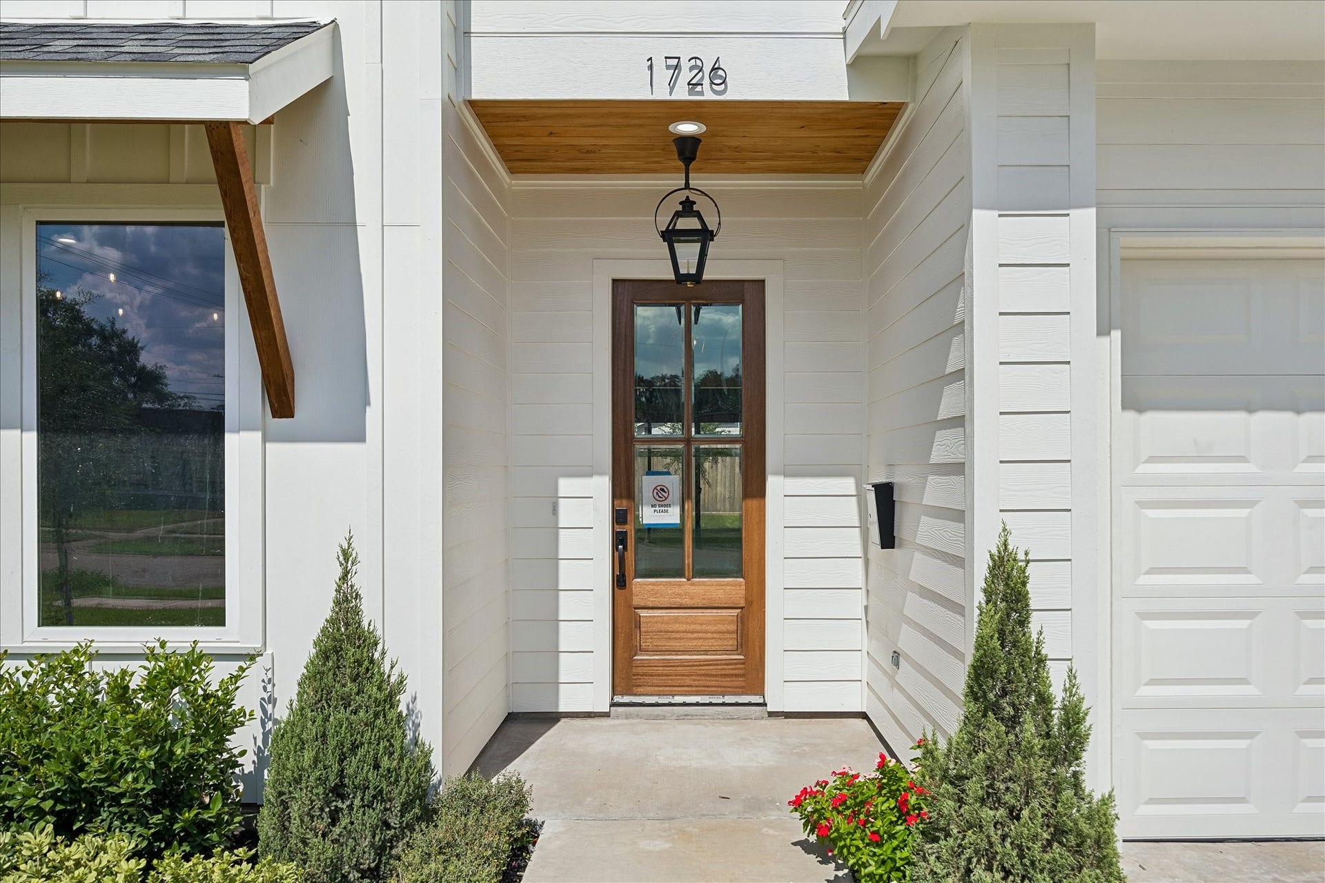 1726 Chantilly Lane, Houston, TX 77018 A wood entry door with a glass panel sits beneath the covered front porch. Lantern lighting and crisp trim frame the approach to the home.