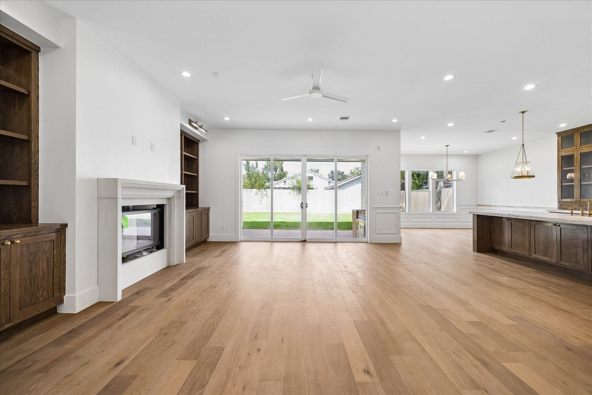 1726 Chantilly Lane, Houston, TX 77018 The main living area opens toward the covered patio through sliding glass doors. The fireplace and flanking built-ins create a focal point, with the kitchen alongside for an easy flow.