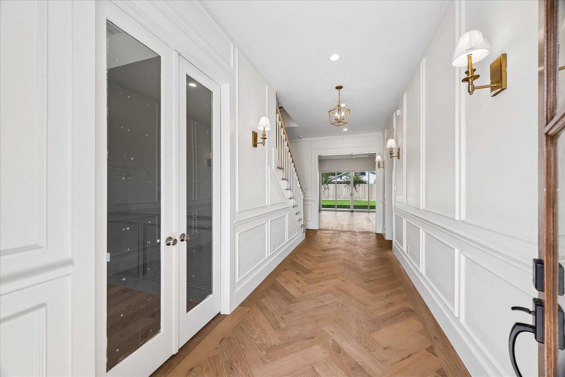 1726 Chantilly Lane, Houston, TX 77018 Paneled walls and herringbone flooring define the entry hall. A glass door opens to the study while the hallway leads toward the main living spaces.
