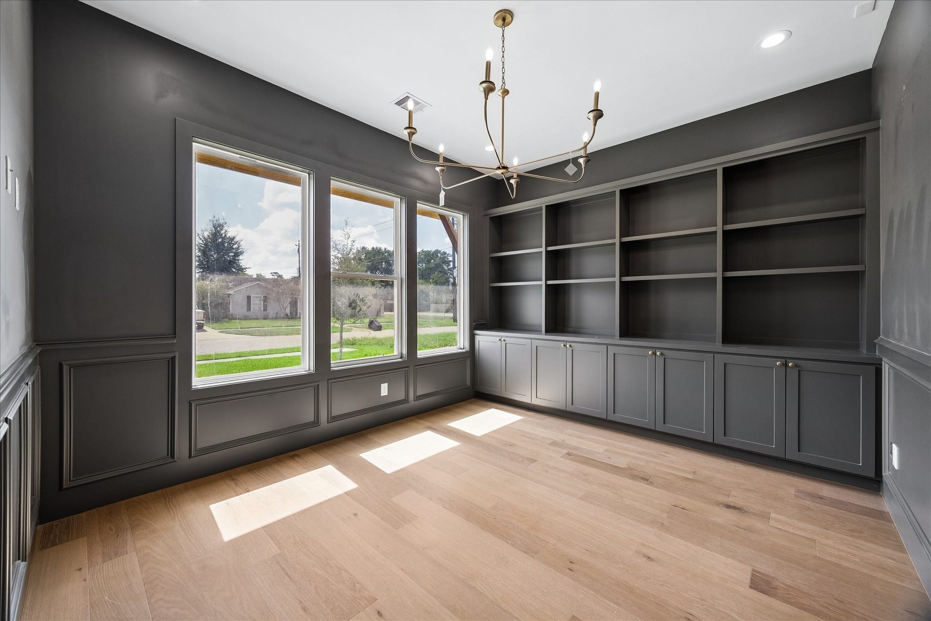 1726 Chantilly Lane, Houston, TX 77018 The dedicated study features deep-toned walls and built-in shelving and cabinetry. A bank of front-facing windows brings natural light across the wood floor.