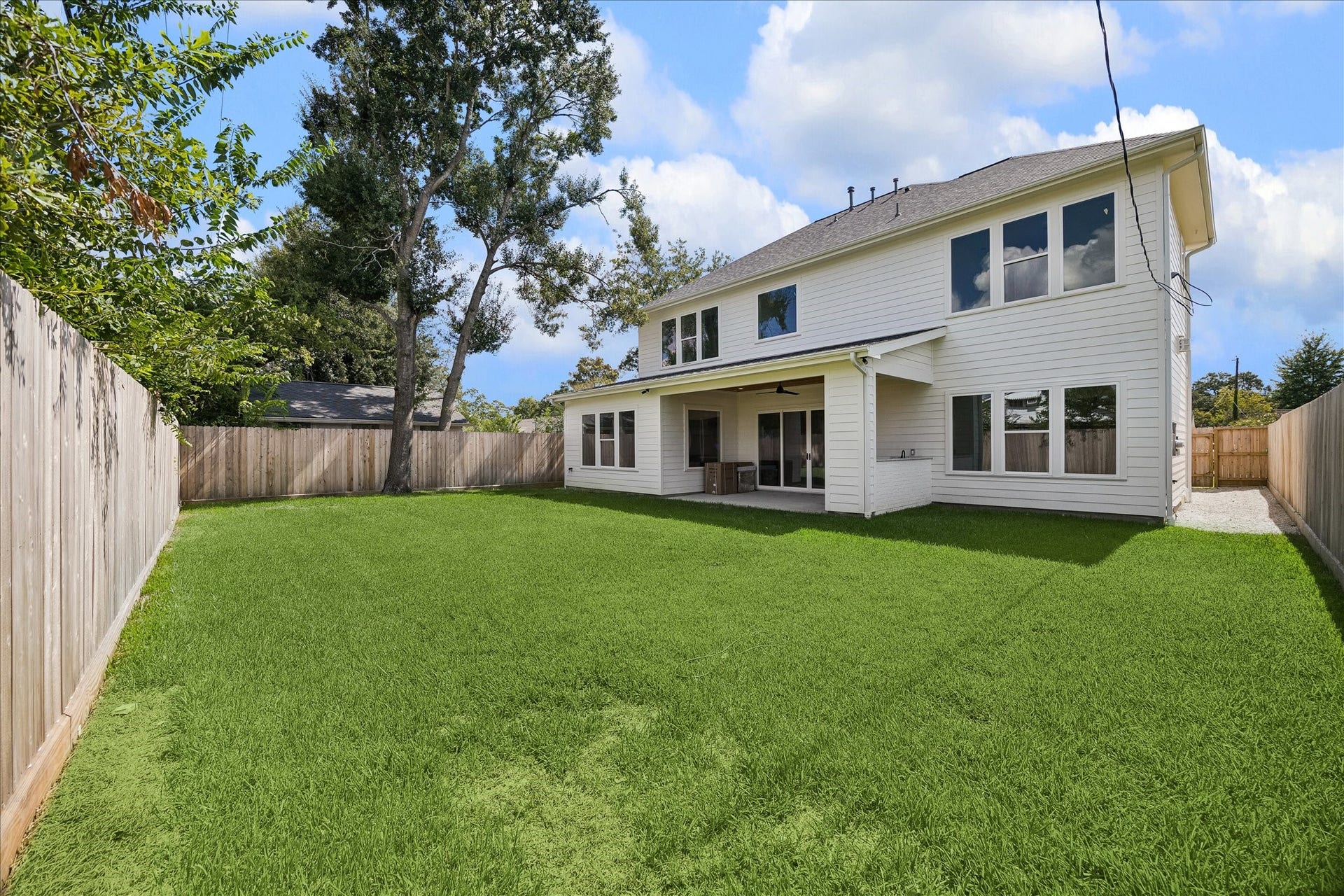 1726 Chantilly Lane, Houston, TX 77018 The rear elevation opens to a covered patio and fenced lawn. Large windows and sliding doors connect the interior gathering spaces with the backyard.