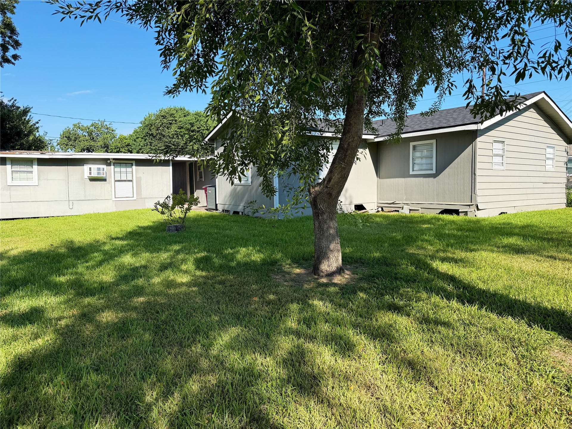 1302 N Avenue R, Freeport, TX 77541 Spacious backyard with plenty of room for outdoor activities, complemented by mature trees that provide natural shade.