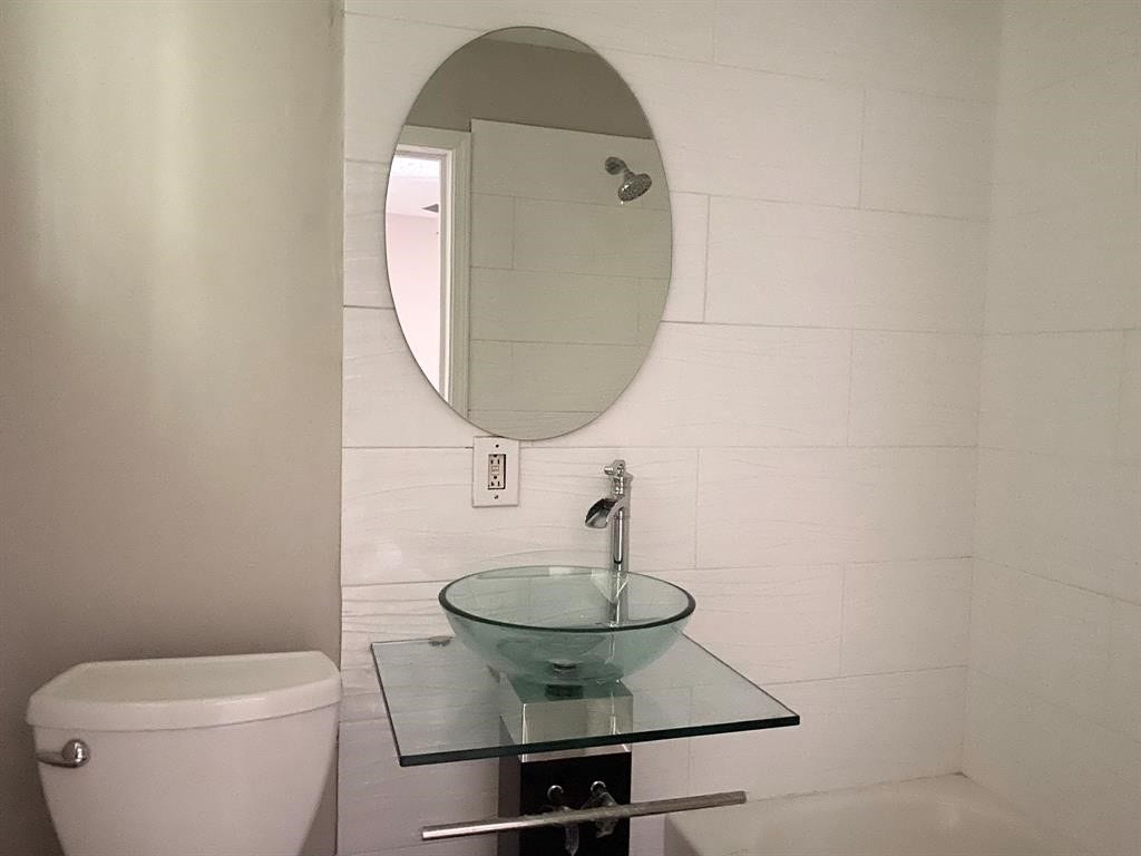 3406 Daphne St Street, #5, Houston, TX 77021 Modern bathroom with sleek glass sink and oval mirror, complemented by a minimalist design.