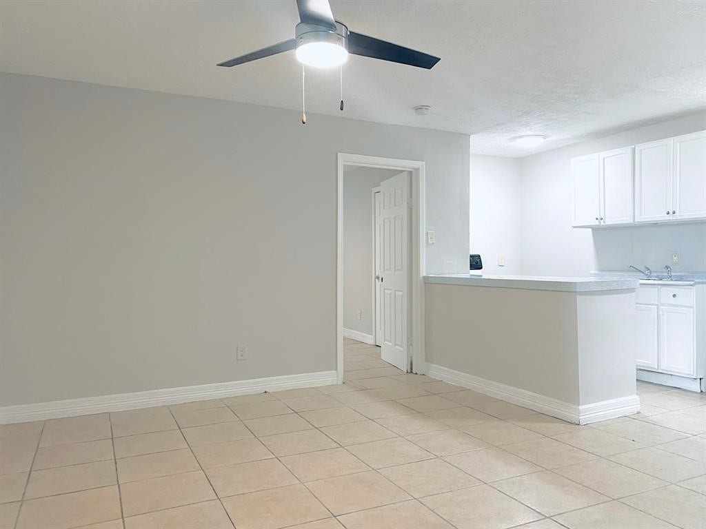 3406 Daphne St Street, #5, Houston, TX 77021 Spacious open-concept living area with neutral tiles, a modern ceiling fan, and a bright kitchen featuring white cabinetry.