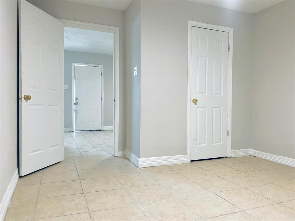 3406 Daphne St Street, #5, Houston, TX 77021 Bright, neutral-toned room with tiled flooring and multiple doorways, offering versatile space and easy access to adjoining areas.