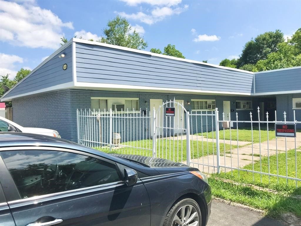 3406 Daphne St Street, #5, Houston, TX 77021 Charming blue brick home with a modern flat roof, surrounded by a secure white fence, offering a neat front yard and convenient driveway access.