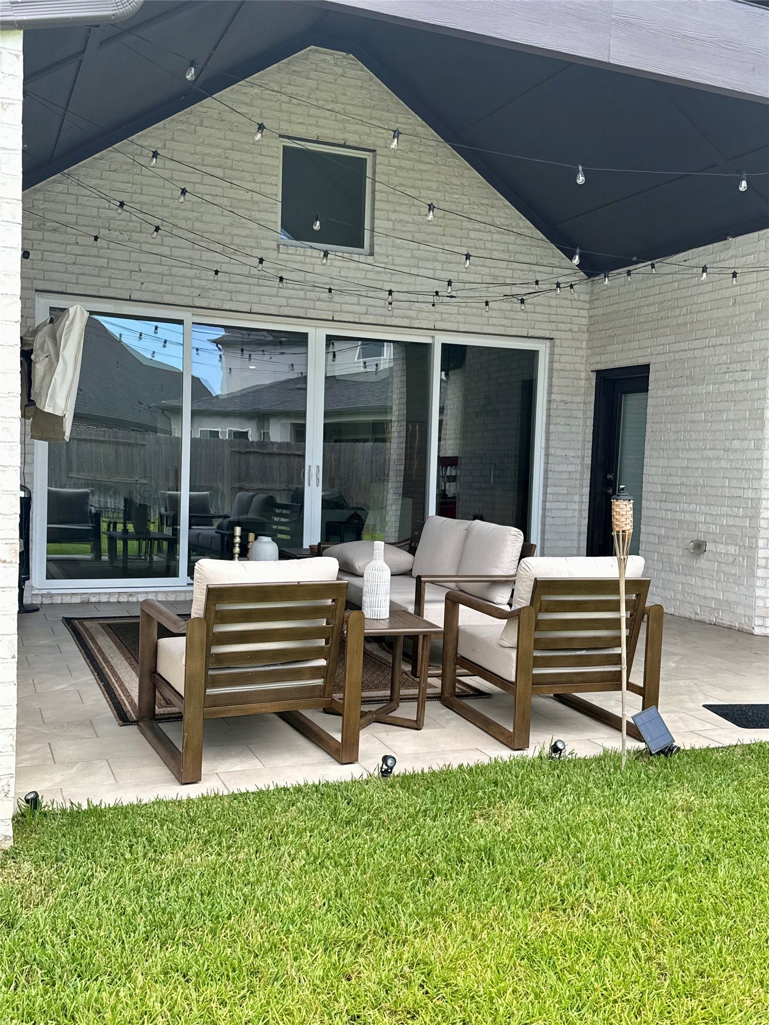 9911 Deep Water Drive, Missouri City, TX 77459 Charming outdoor patio with cozy seating, string lights, and a spacious sliding door, perfect for relaxing and entertaining.