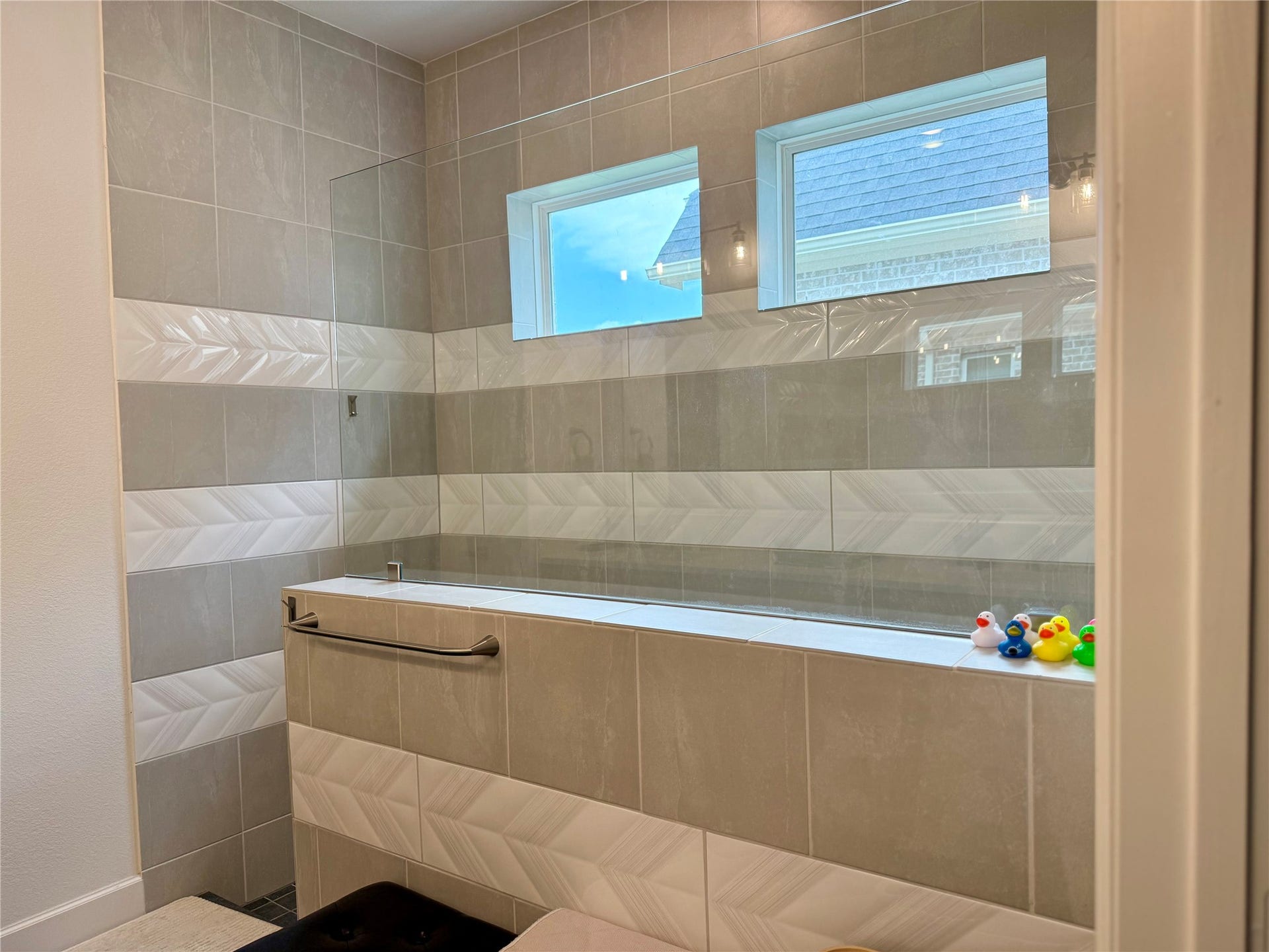 9911 Deep Water Drive, Missouri City, TX 77459 Elegant bathroom featuring a modern soaking tub with stylish tile surround and two bright windows, creating a serene and inviting atmosphere.