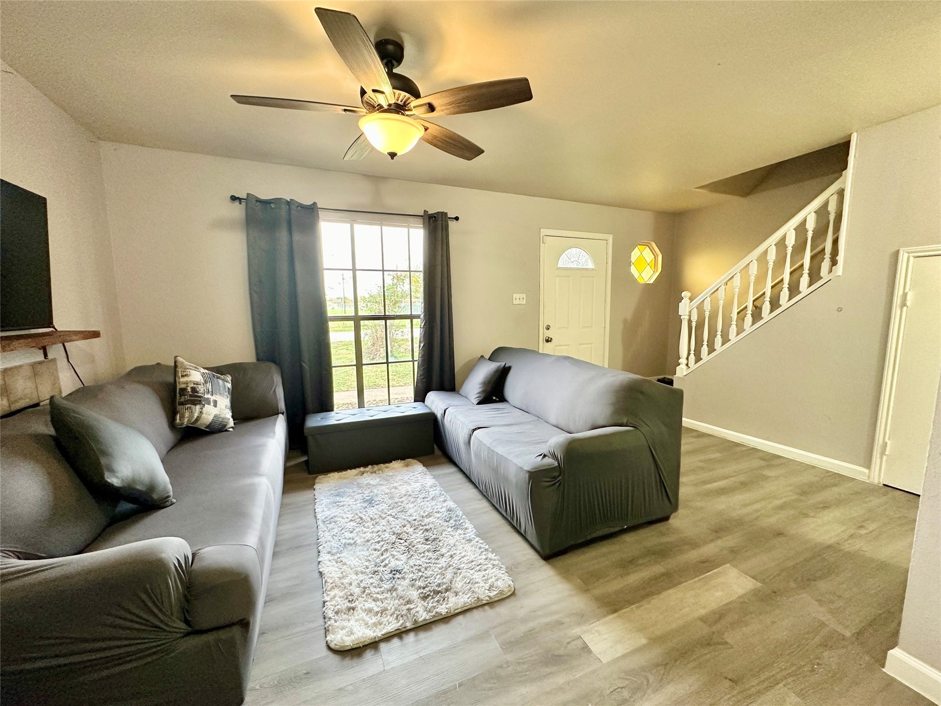 4114 Hartt Lane, Houston, TX 77025 Charming living room features lighted ceiling fan, wood vinyl plank flooring and wood burning fireplace.