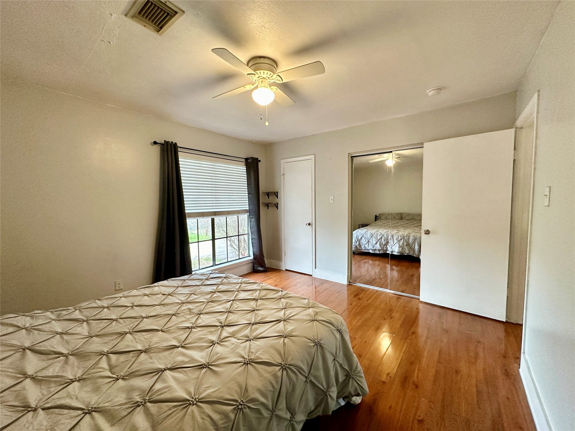 4114 Hartt Lane, Houston, TX 77025 Primary bedroom features closet w/ full length mirrored sliding doors, hard flooring, lighted ceiling fan.