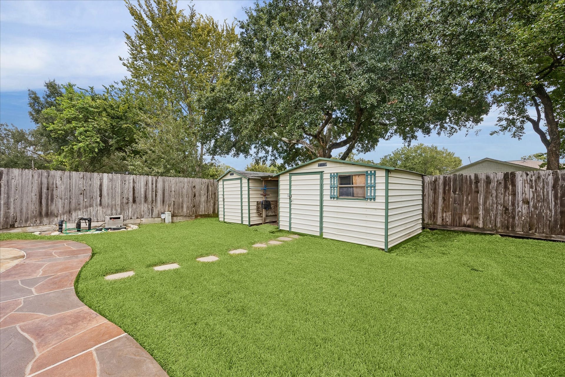 13626 Greenridge Drive, Sugar Land, TX 77498 Spacious backyard featuring a well-maintained lawn, a storage shed and stone pathway surrounded by mature trees.