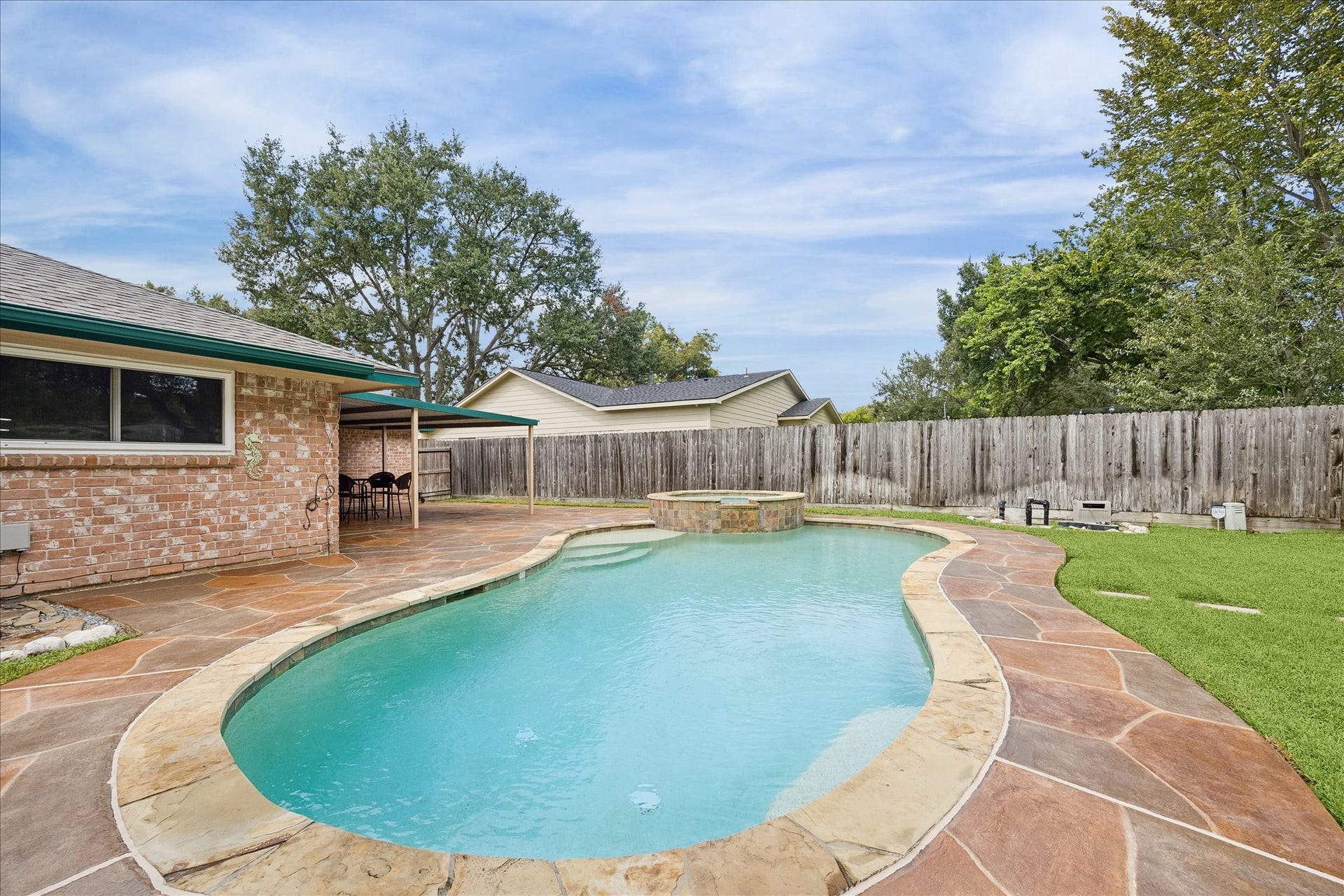 13626 Greenridge Drive, Sugar Land, TX 77498 Relax in your private backyard oasis featuring a sparkling pool with a spa, surrounded by a spacious stone patio perfect for entertaining.