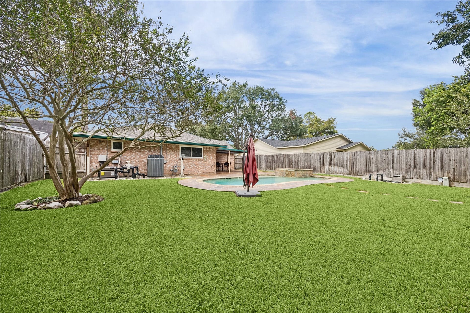 13626 Greenridge Drive, Sugar Land, TX 77498 Spacious backyard with lush green lawn, featuring a refreshing pool and a charming brick exterior, perfect for outdoor relaxation and entertainment.