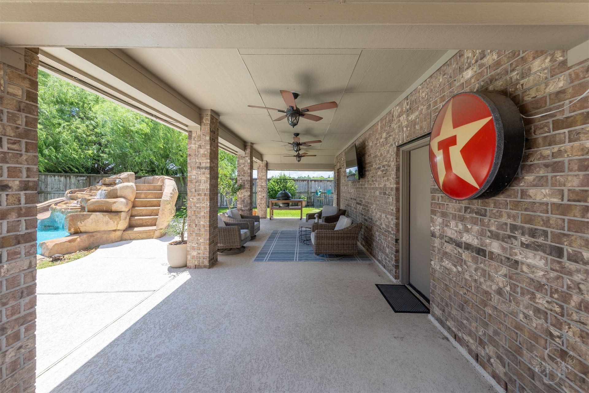 5835 Caspian Falls Lane, Fulshear, TX 77441 The oversized covered patio offers multiple seating areas, ceiling fans and plenty of room to relax while overlooking the pool and waterfall. Whether hosting friends or enjoying a quiet evening, this outdoor living space was designed for year-round enjoyment.