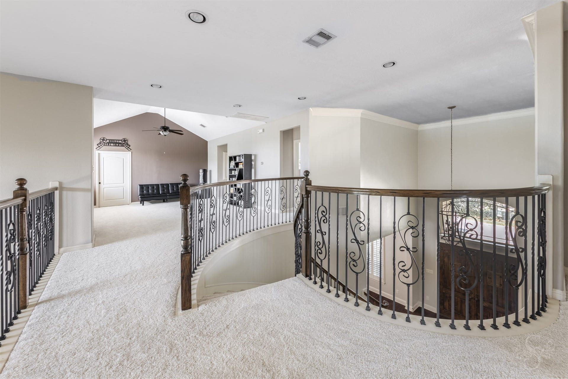 5835 Caspian Falls Lane, Fulshear, TX 77441 A dramatic curved staircase with iron balusters creates a stunning architectural focal point, while the expansive upstairs landing overlooks the grand entry below. This impressive space provides a beautiful transition to the home's entertainment areas and secondary bedrooms.
