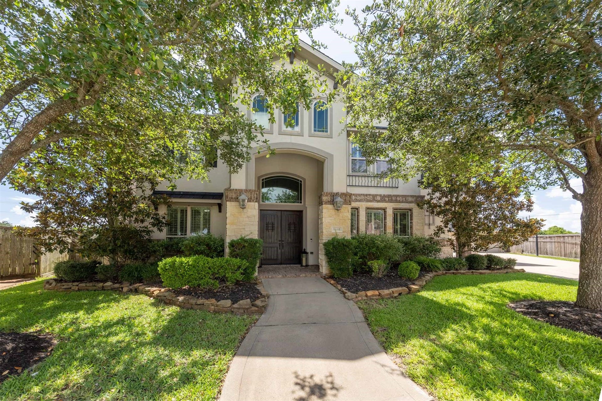 5835 Caspian Falls Lane, Fulshear, TX 77441 Framed by mature trees and professional landscaping, this impressive stucco and stone elevation creates a memorable first impression. The grand covered entry and custom double doors set the stage for the exceptional features found throughout the home.