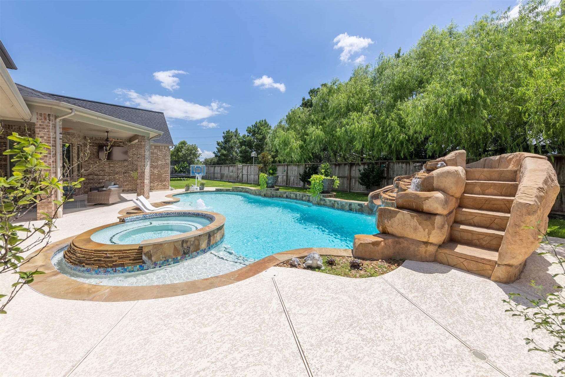 5835 Caspian Falls Lane, Fulshear, TX 77441 A dramatic rock waterfall and slide create a true resort-style experience right at home. Mature trees, lush landscaping and a large backyard complete this exceptional outdoor retreat.