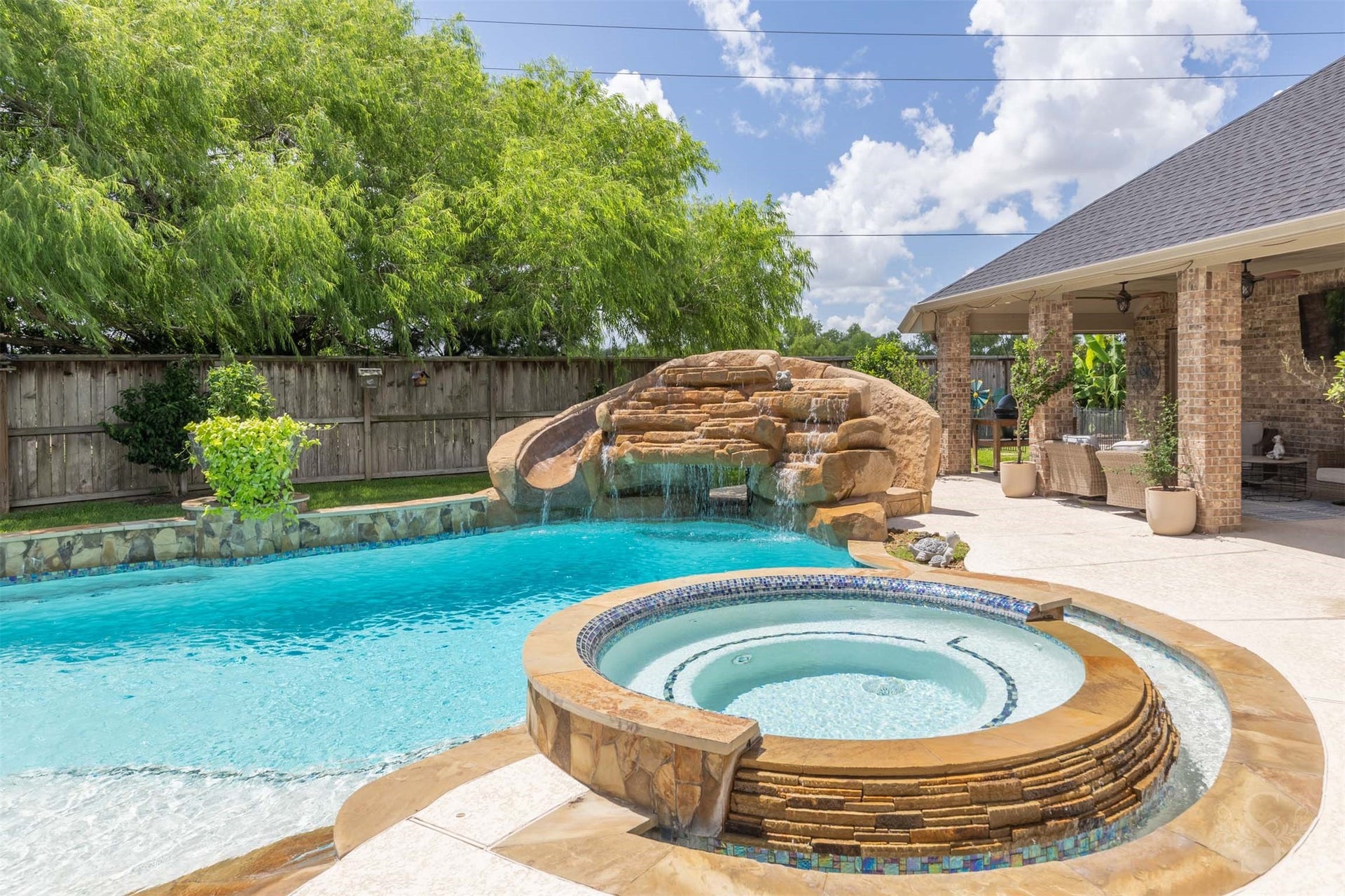 5835 Caspian Falls Lane, Fulshear, TX 77441 The resort-style pool is highlighted by a raised spa and impressive rock waterfall with cascading water features. This backyard was designed for unforgettable summer days and weekend gatherings.
