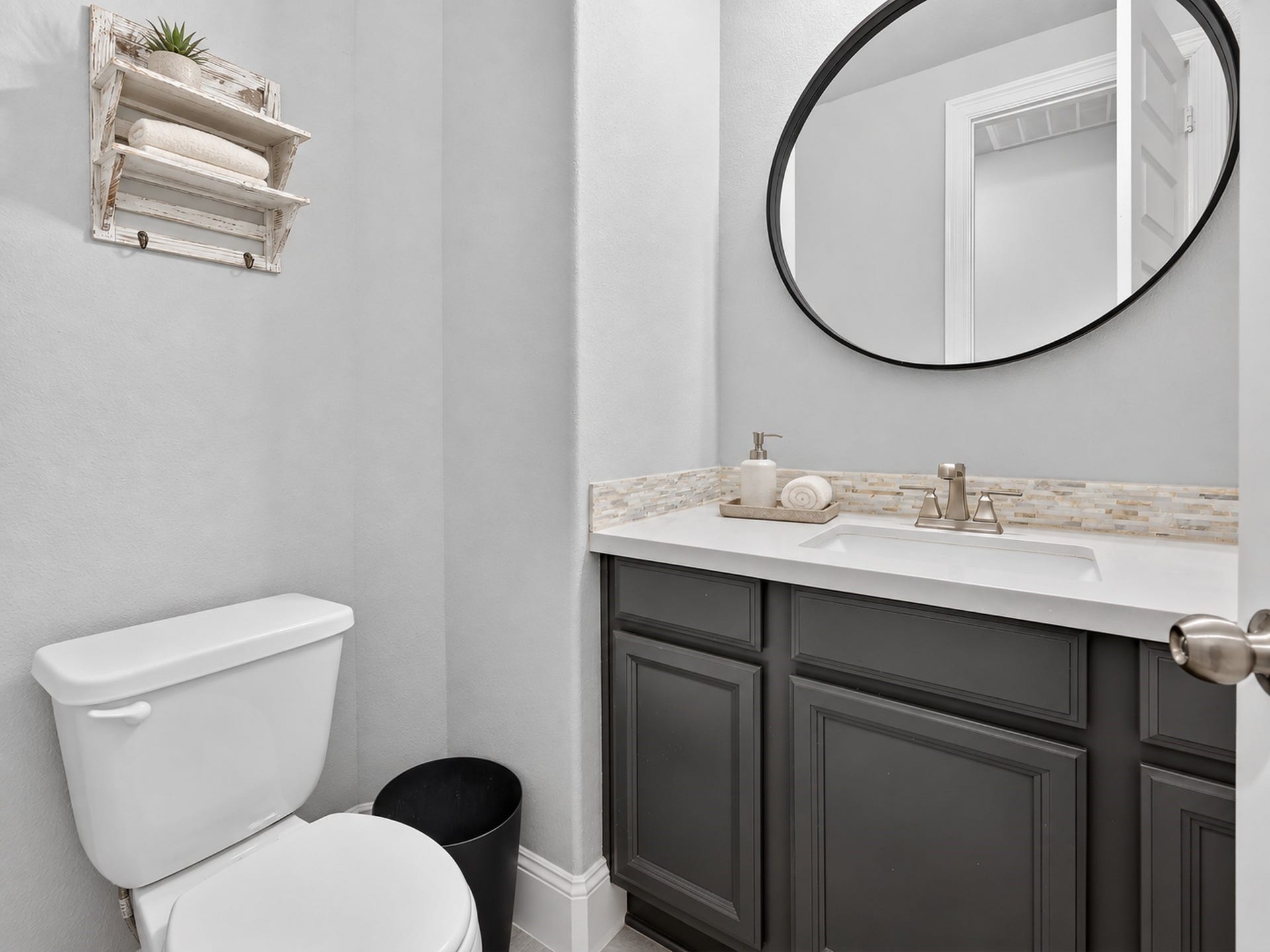 6714 Wellbrook Falls Lane, Katy, TX 77493 Half bath features a dark vanity, light countertop, and tile flooring. (virtually staged)