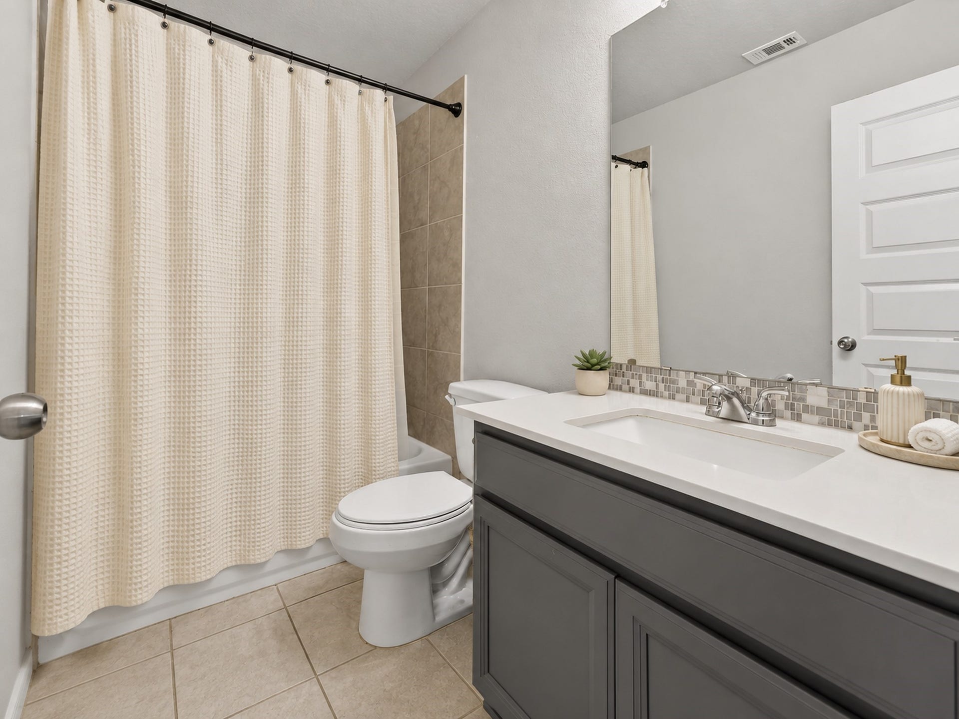 6714 Wellbrook Falls Lane, Katy, TX 77493 Full bath features a tub-shower combination, tile flooring, and a dark vanity. (virtually staged)