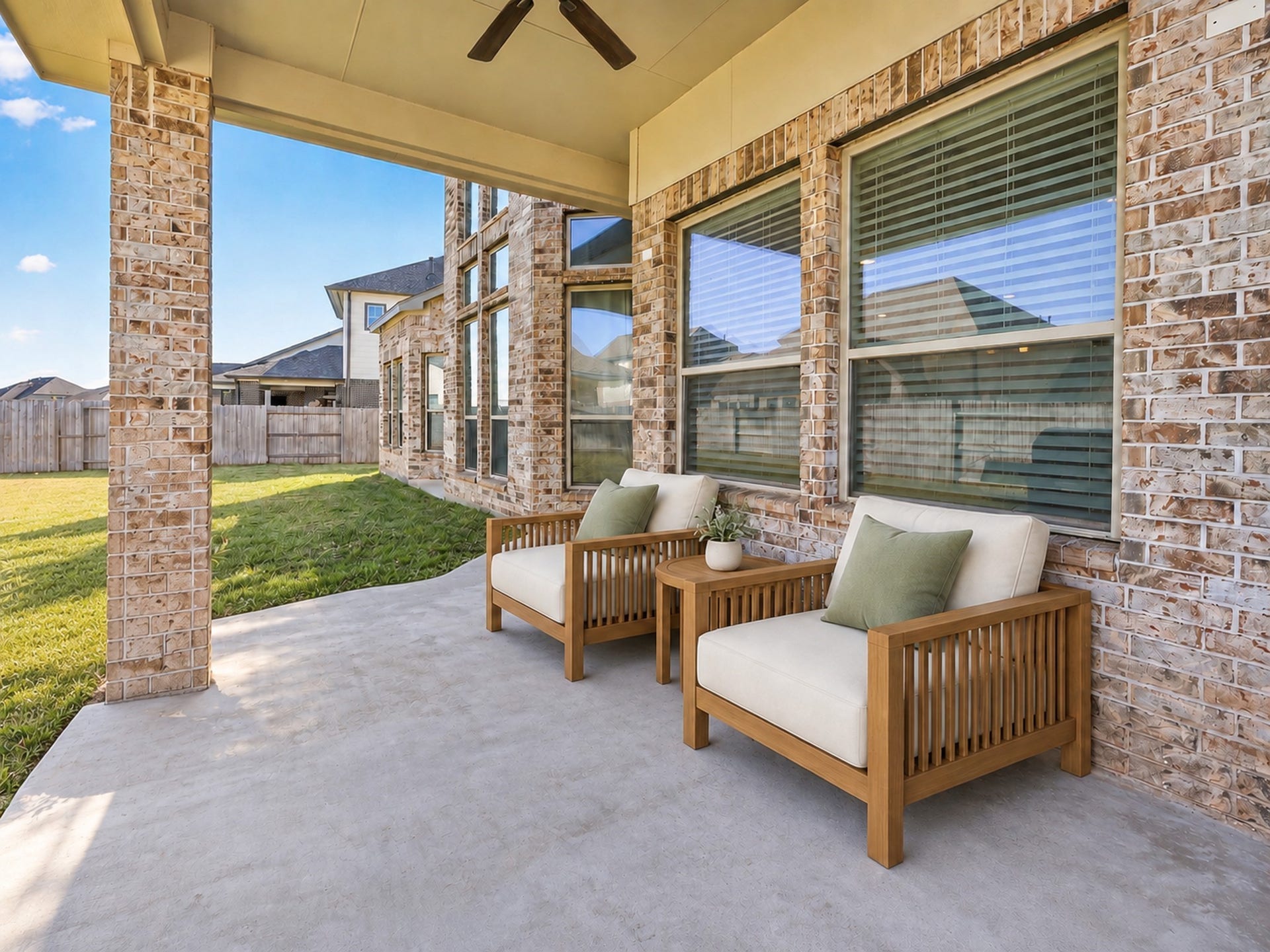 6714 Wellbrook Falls Lane, Katy, TX 77493 Covered patio features a ceiling fan, brick columns, and backyard views. (virtually staged)