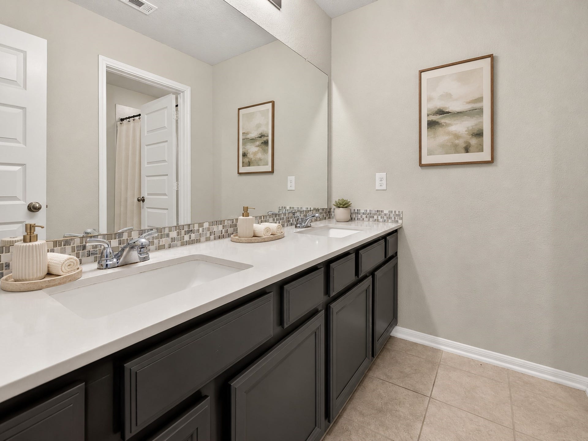 6714 Wellbrook Falls Lane, Katy, TX 77493 Bathroom features a dual-sink vanity, expansive mirror, and tile flooring. (virtually staged)