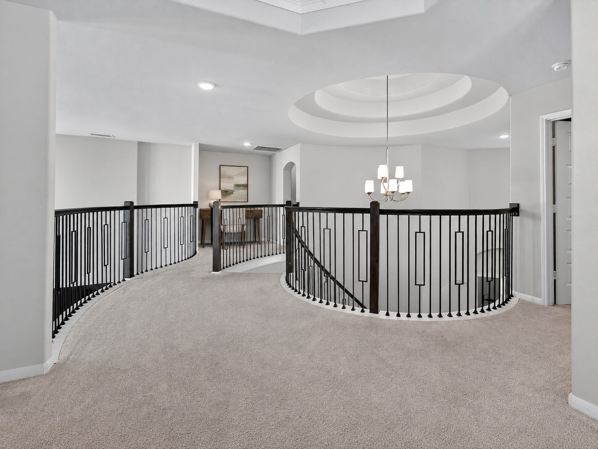 6714 Wellbrook Falls Lane, Katy, TX 77493 Upstairs landing features curved railings and decorative ceiling details overlooking the foyer. (virtually staged)