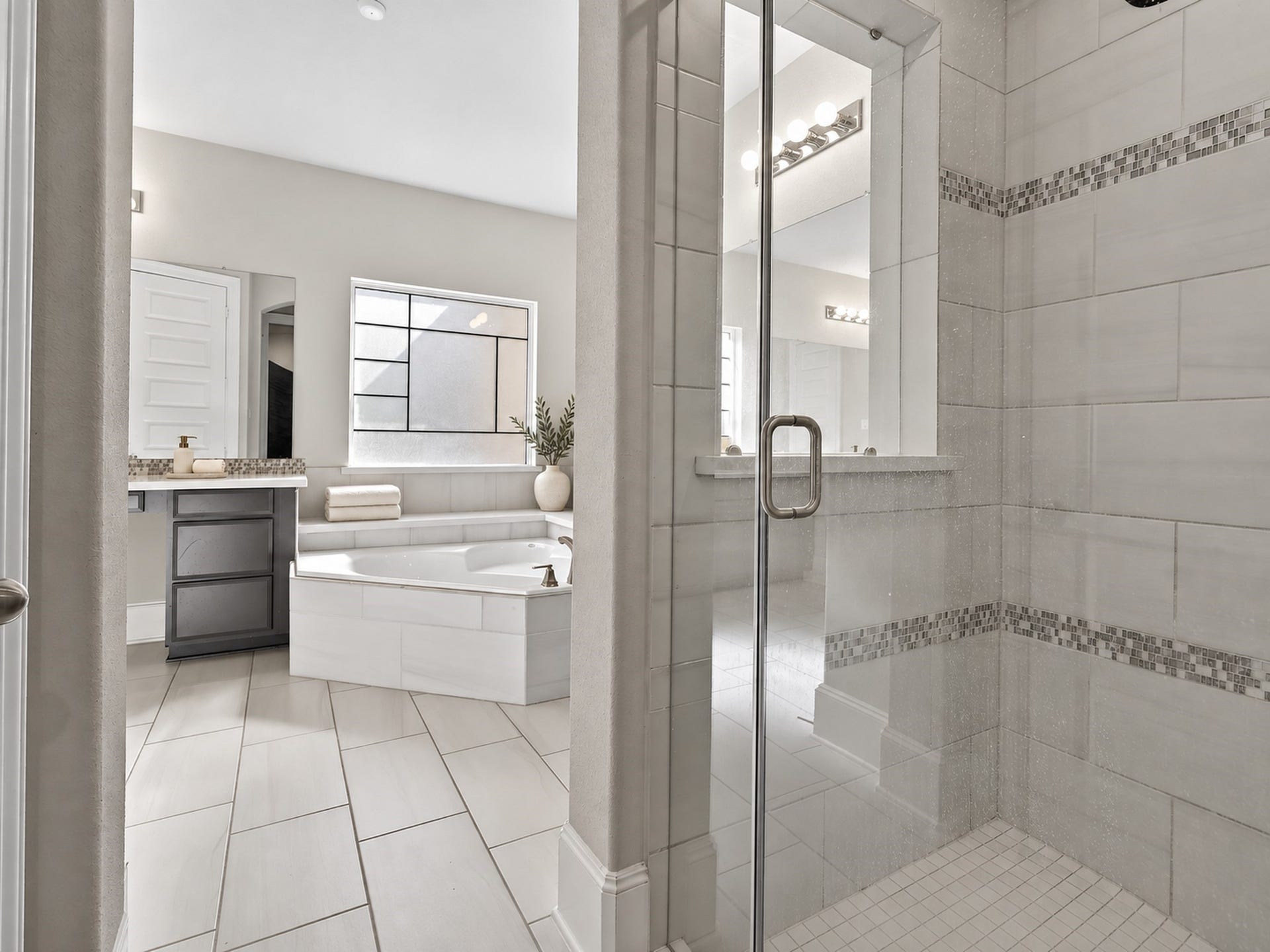 6714 Wellbrook Falls Lane, Katy, TX 77493 Glass-enclosed shower features tile walls and decorative mosaic accents. (virtually staged)