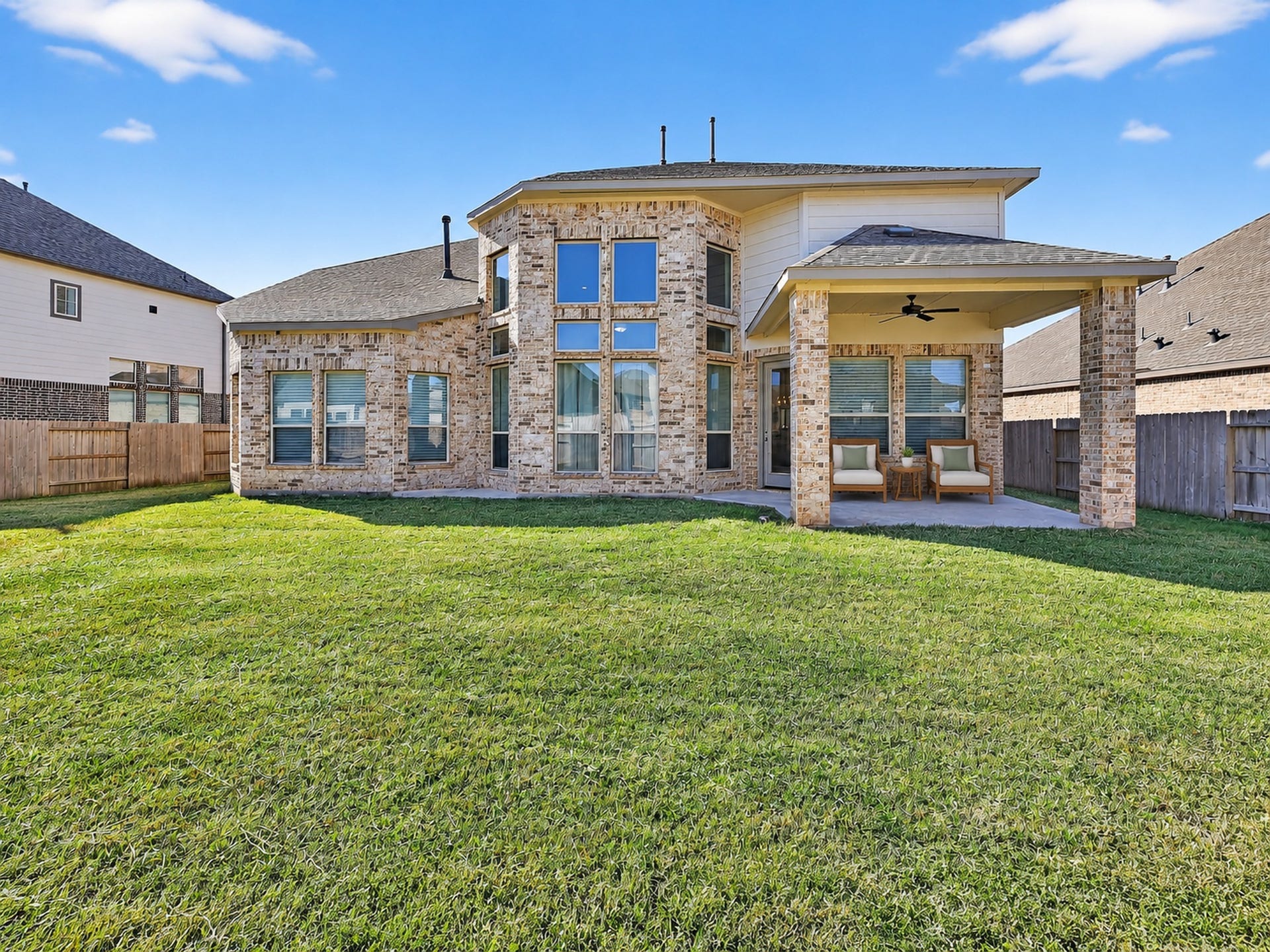 6714 Wellbrook Falls Lane, Katy, TX 77493 Rear exterior highlights expansive windows, a covered patio, and a fenced backyard. (virtually staged)