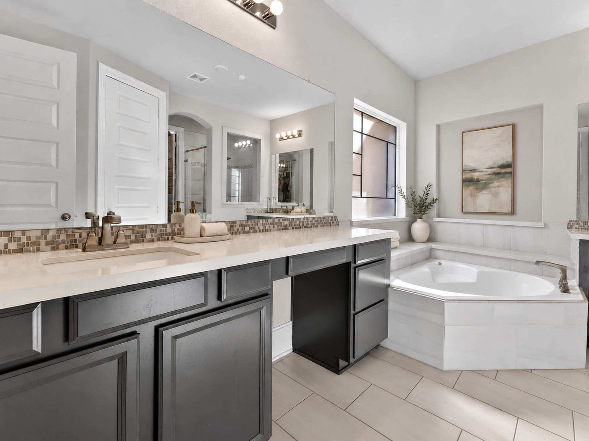 6714 Wellbrook Falls Lane, Katy, TX 77493 Primary bath features dual sinks, a vanity seating area, and a corner soaking tub. (virtually staged)