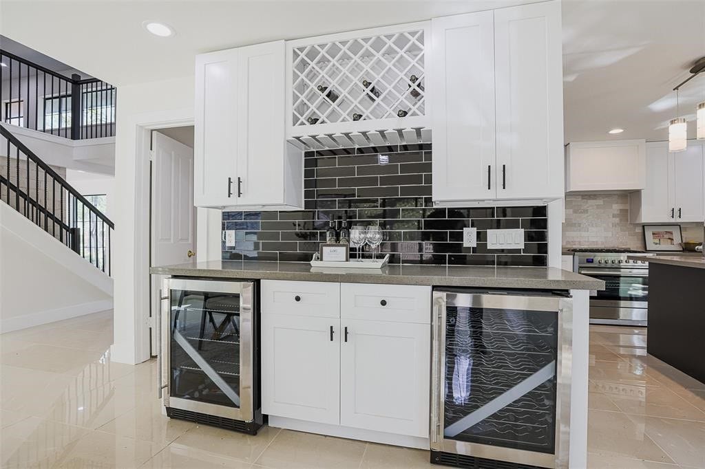 5614 Indian Circle, Houston, TX 77056 Stylish bar area featuring shaker-style cabinets and a striking black backsplash, offering a sleek contrast. The design blends timeless elegance with modern sophistication, creating the perfect space for entertaining.