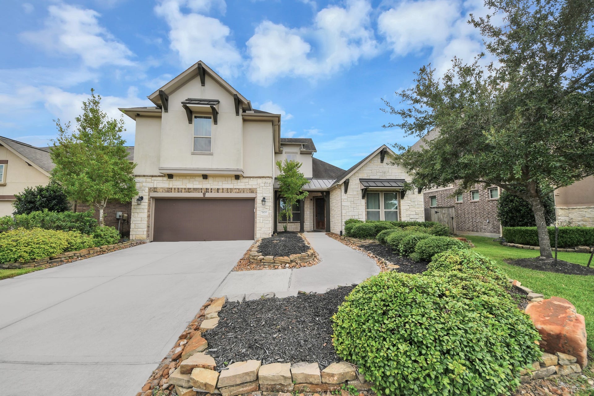 Impressive two-story home with stone accents, architectural details, and manicured landscaping.