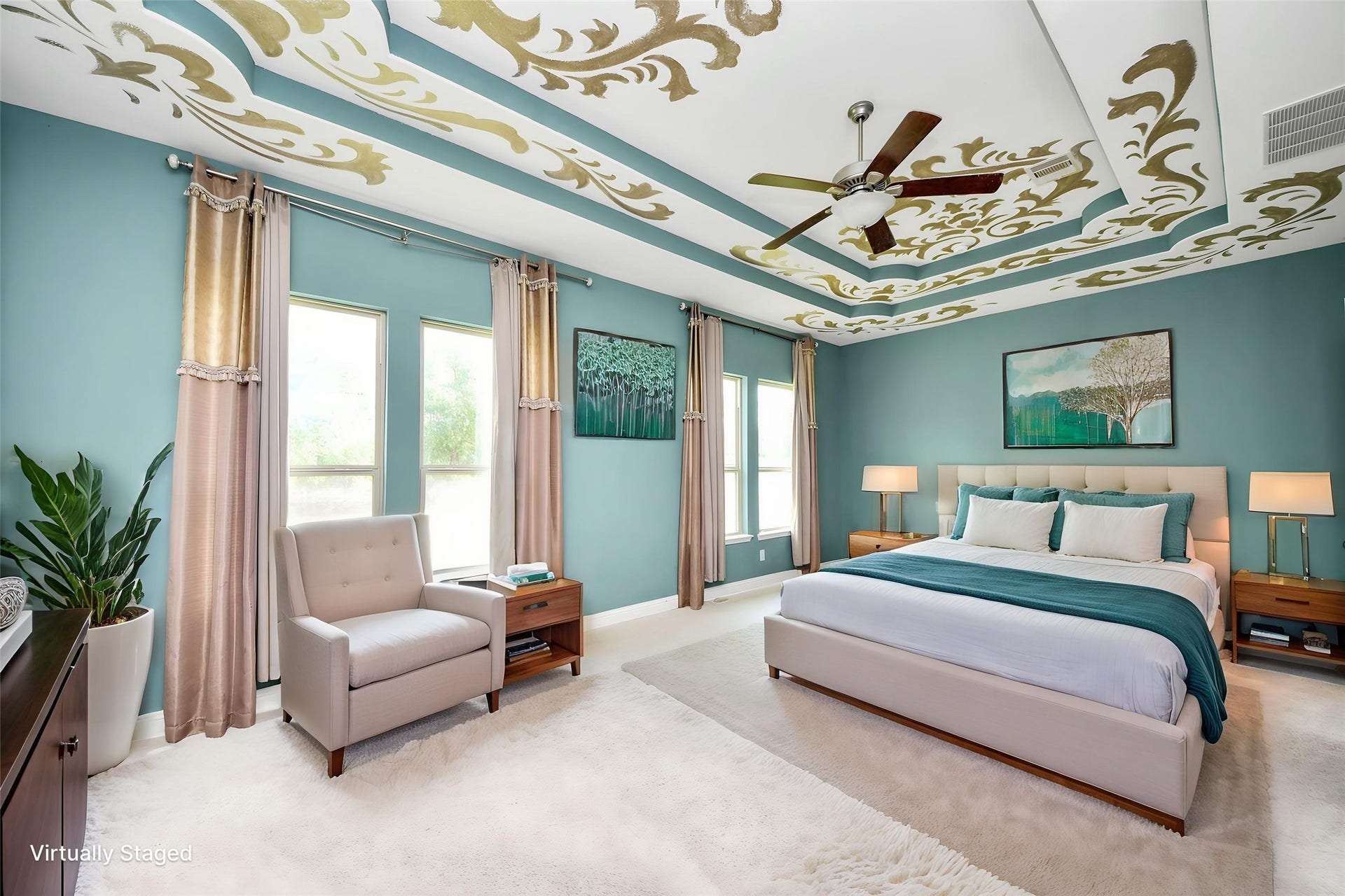 Another view of the generously sized primary suite showcasing the distinctive decorative ceiling, ceiling fan, and ample space for a sitting area. Virtually staged.
