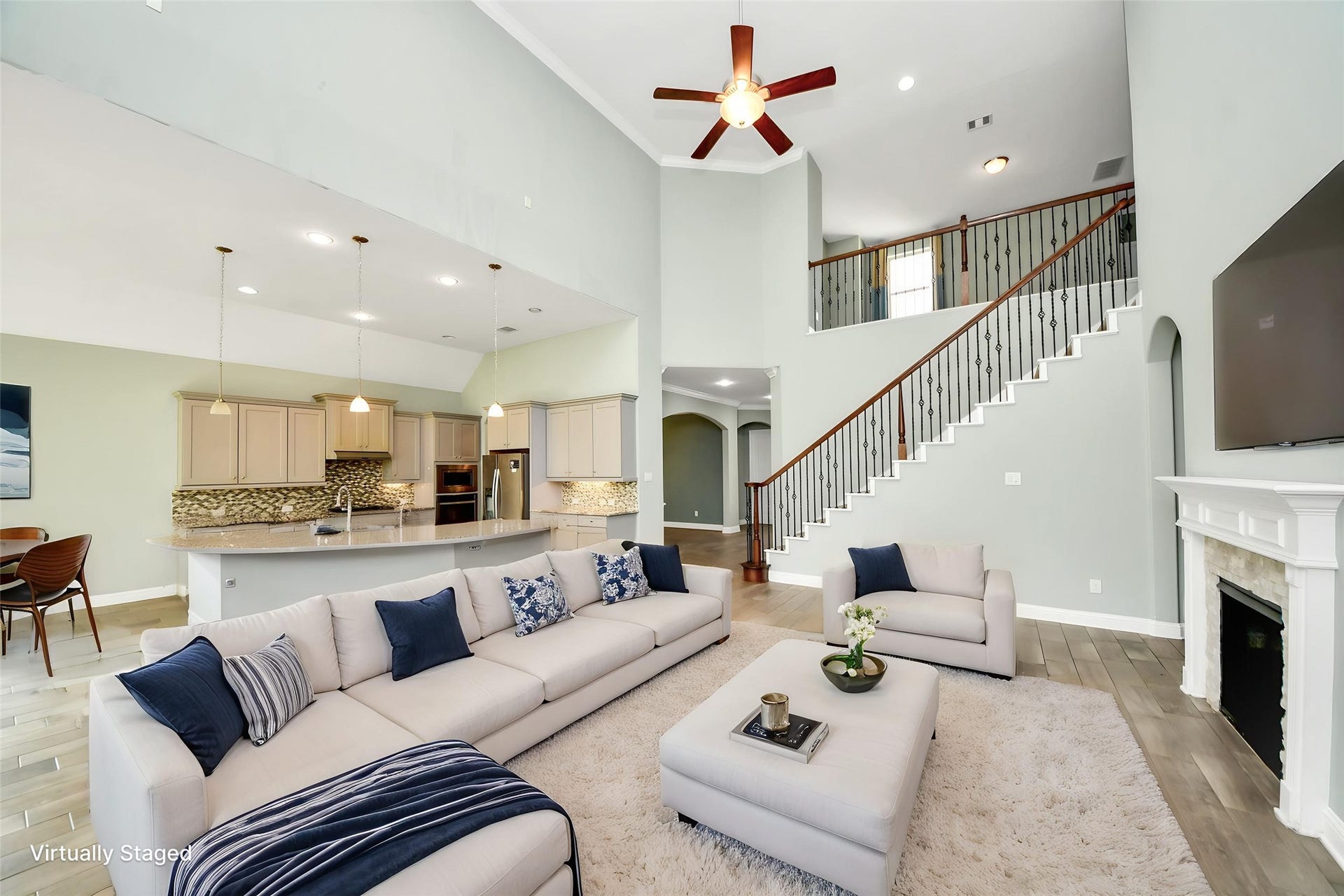 Virtually Staged  Spacious family room featuring fireplace, architectural niches, staircase views, and flexible entertaining space.