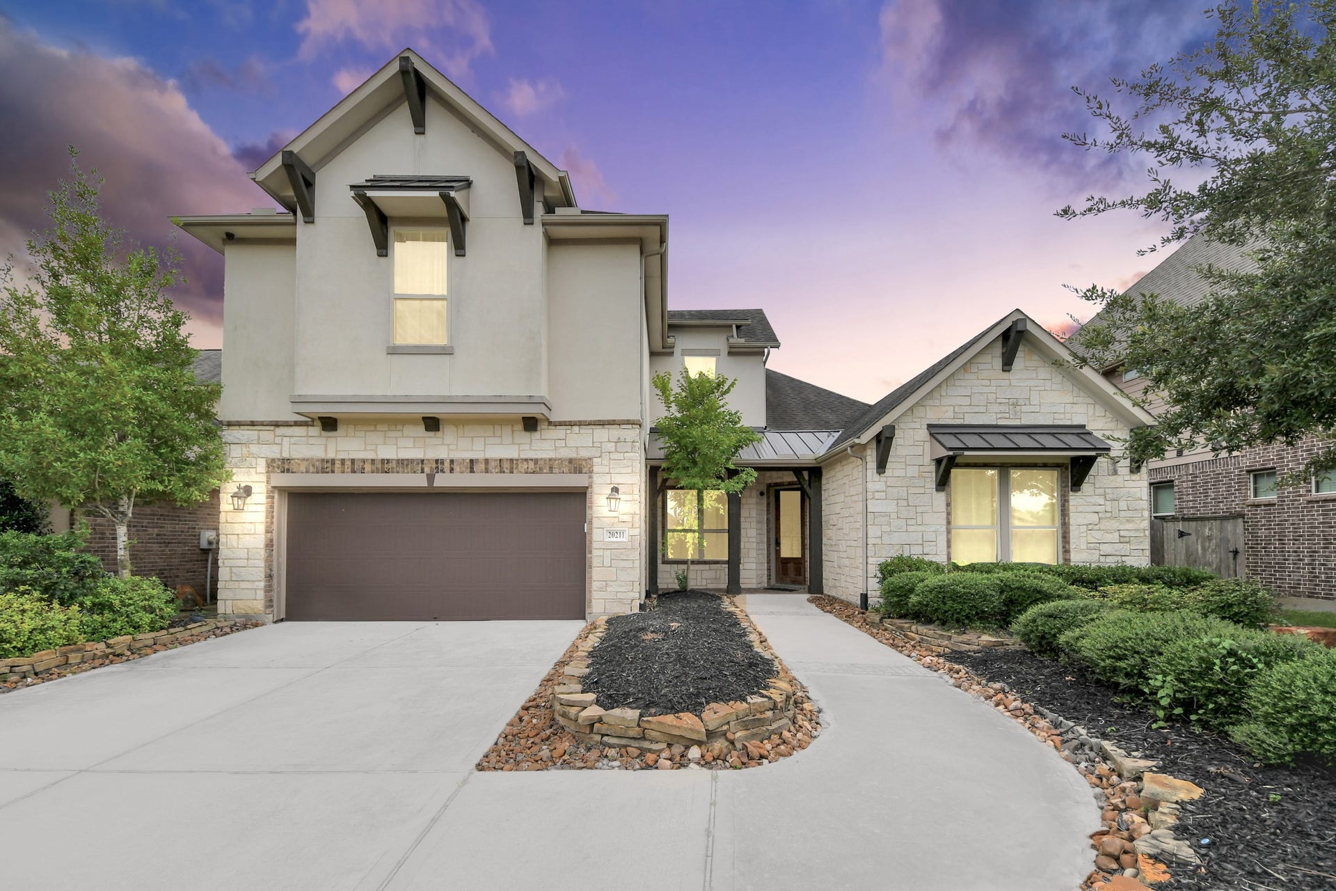 Striking front elevation showcased at twilight with warm exterior lighting and an inviting covered entry.