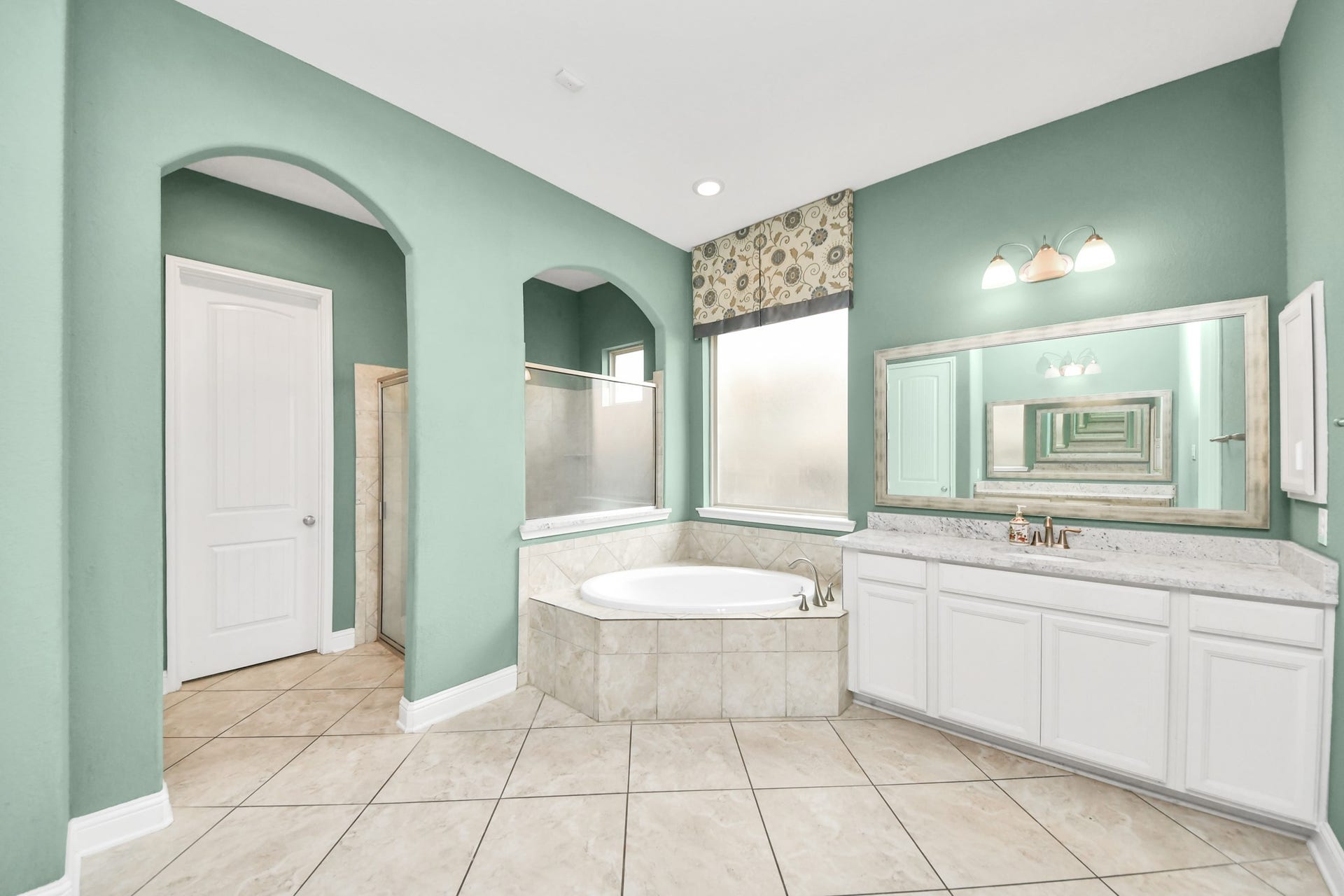 Spacious primary bath featuring a large soaking tub, separate walk-in shower, dual vanity areas, and abundant natural light.