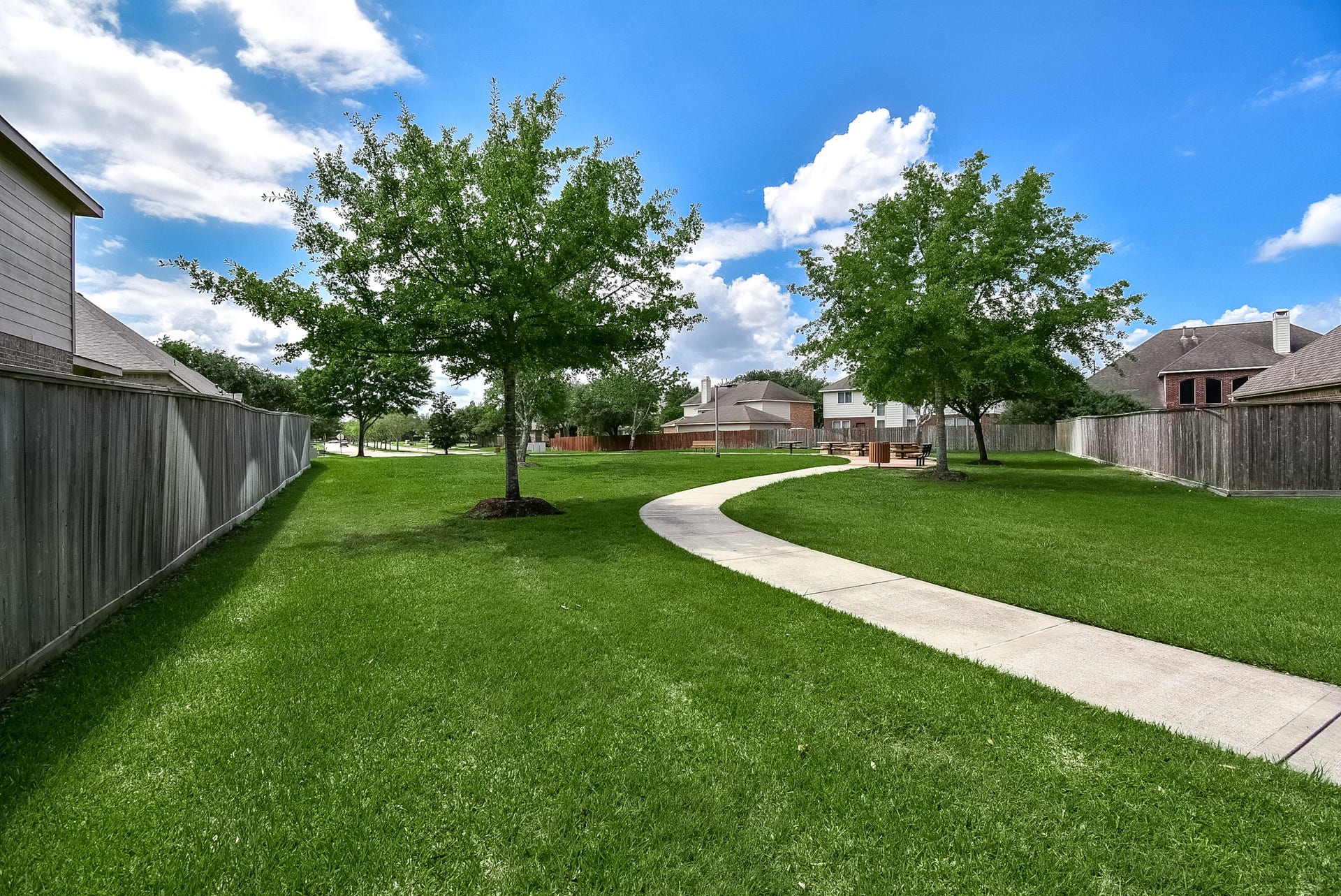 Side yard with sidewalk leading to small pocket park.