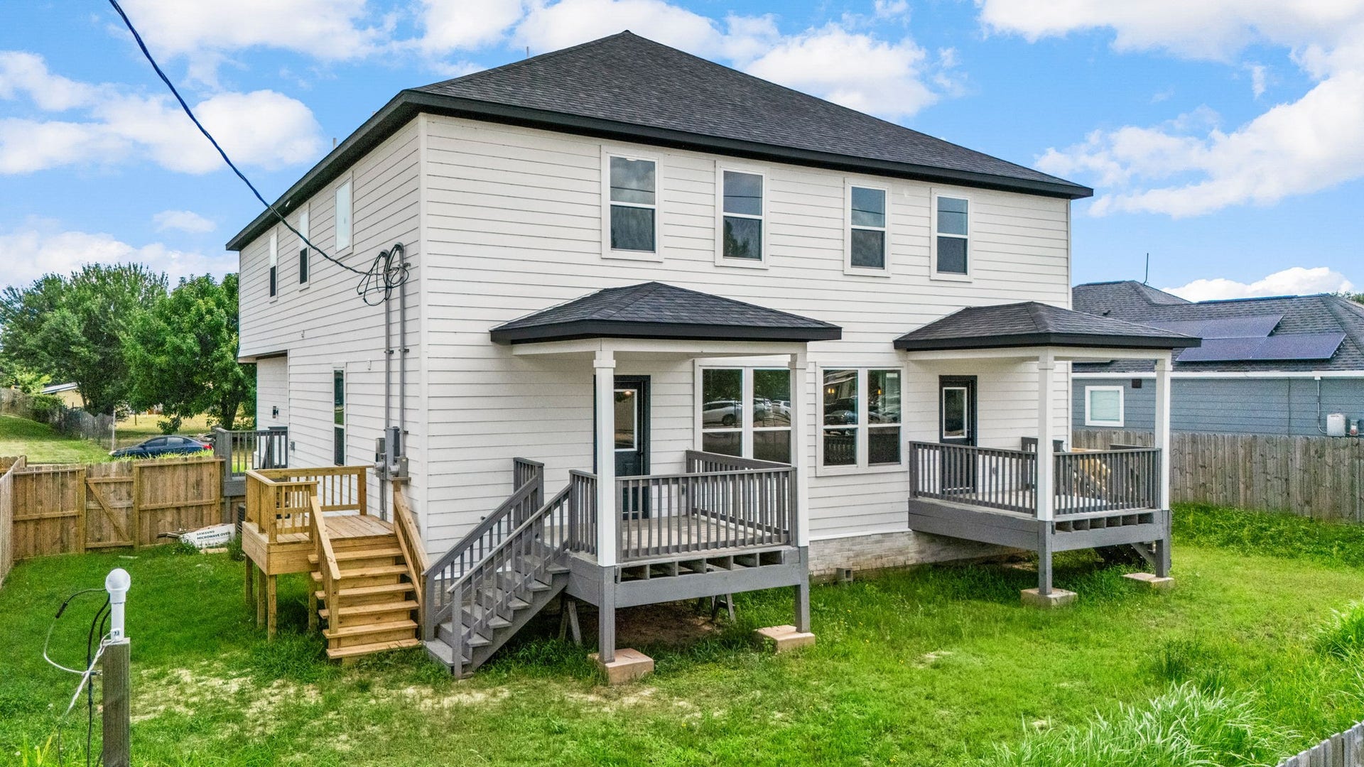 Spacious two-story home with a modern exterior, featuring multiple decks and a fenced backyard, ideal for outdoor activities and entertaining.