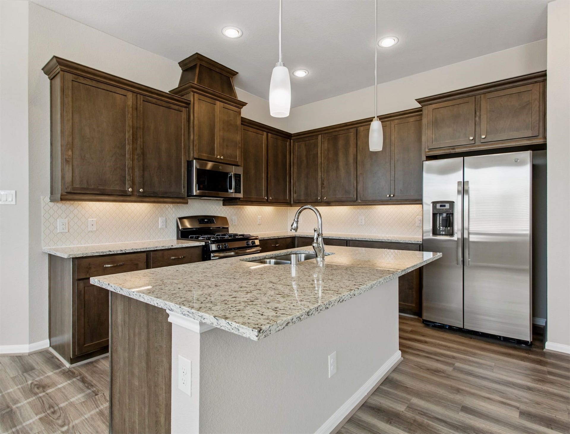 2511 Bordelon Lane, Missouri City, TX 77459 With an abundance of cabinet space, extended island with bar area and beautiful wood tile, this modern kitchen is designed with your every convenience in mind.