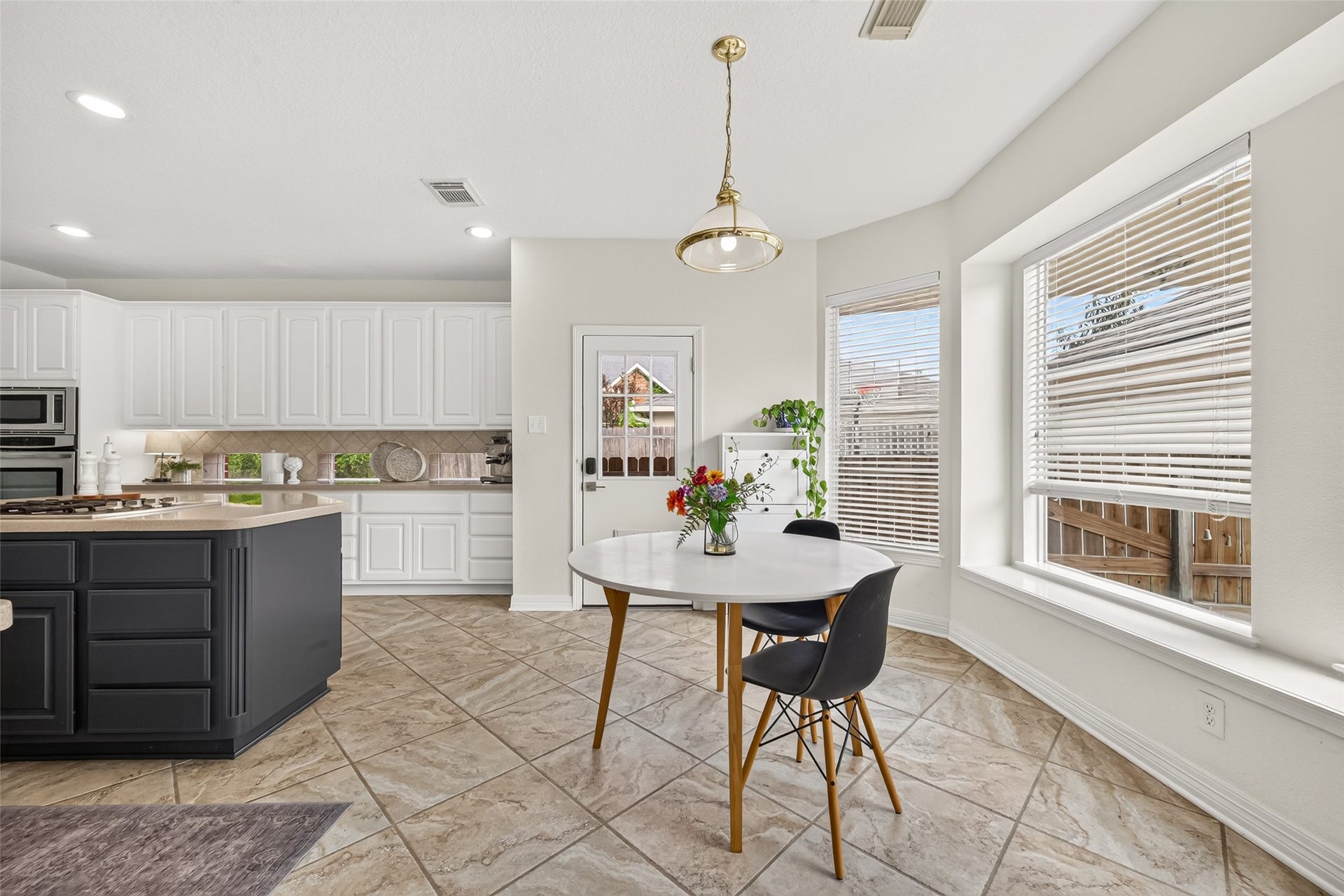 kitchen featuring abundant cabinetry, a central island with stainless steel appliances, and a cozy breakfast nook with bay windows.