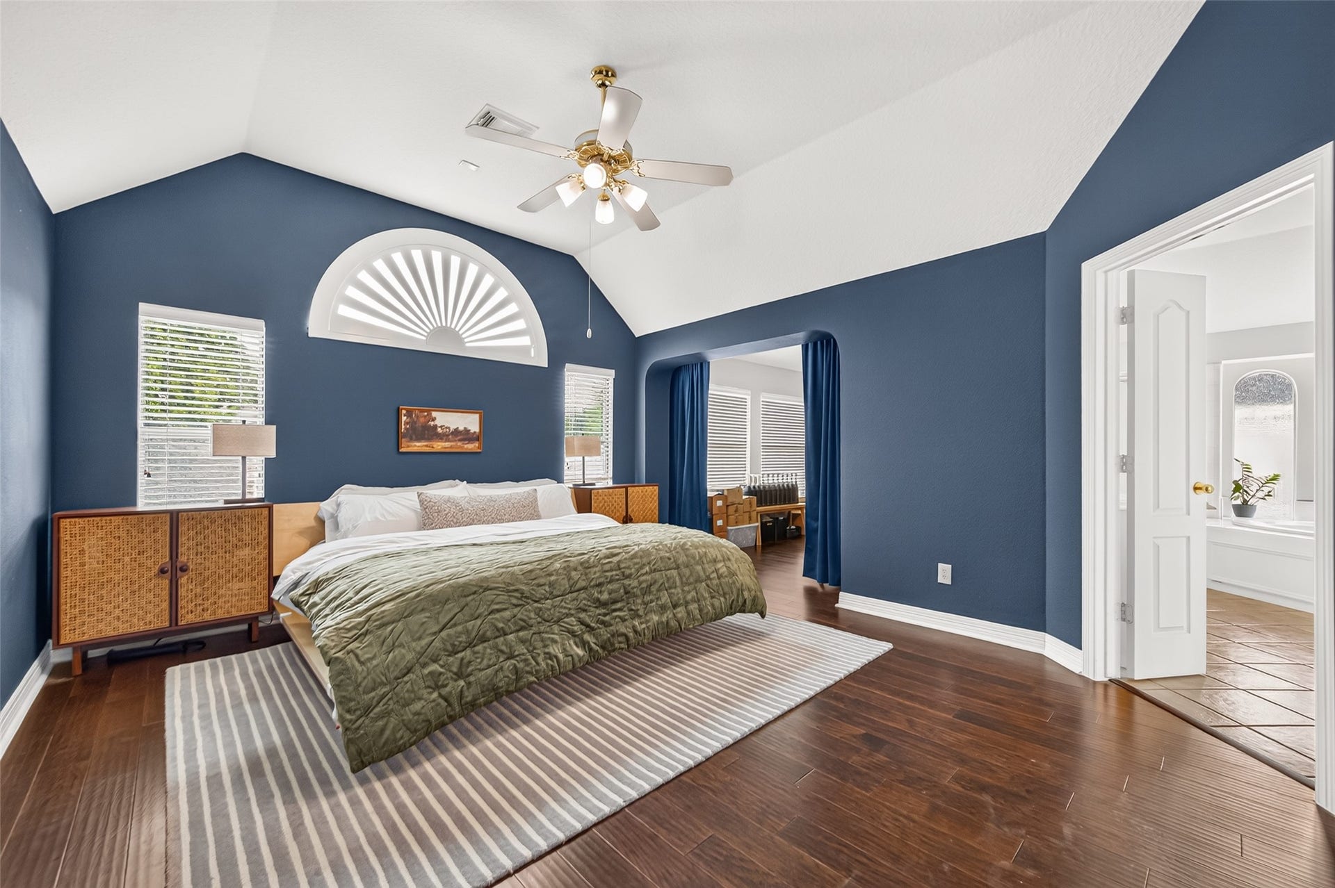Primary bedroom featuring vaulted ceilings, rich hardwood flooring.