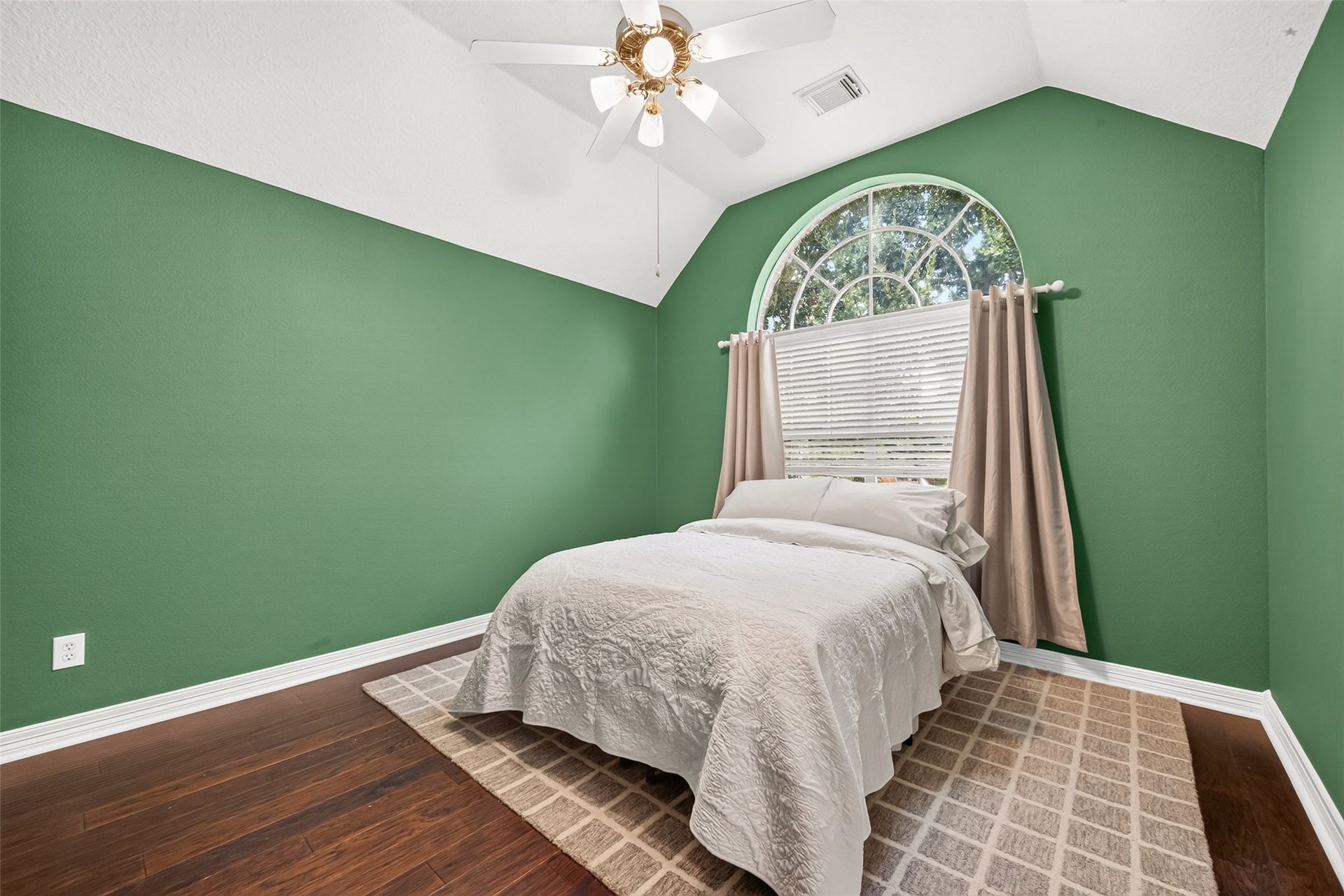 Second floor bedroom featuring vaulted ceiling, arched window.